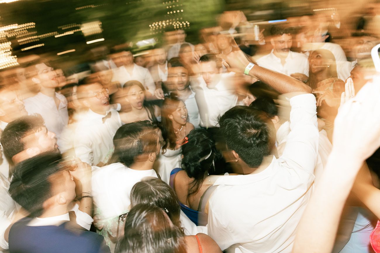 A crowded dance floor filled with people dancing and moving in a blurred motion at a nightclub or party.