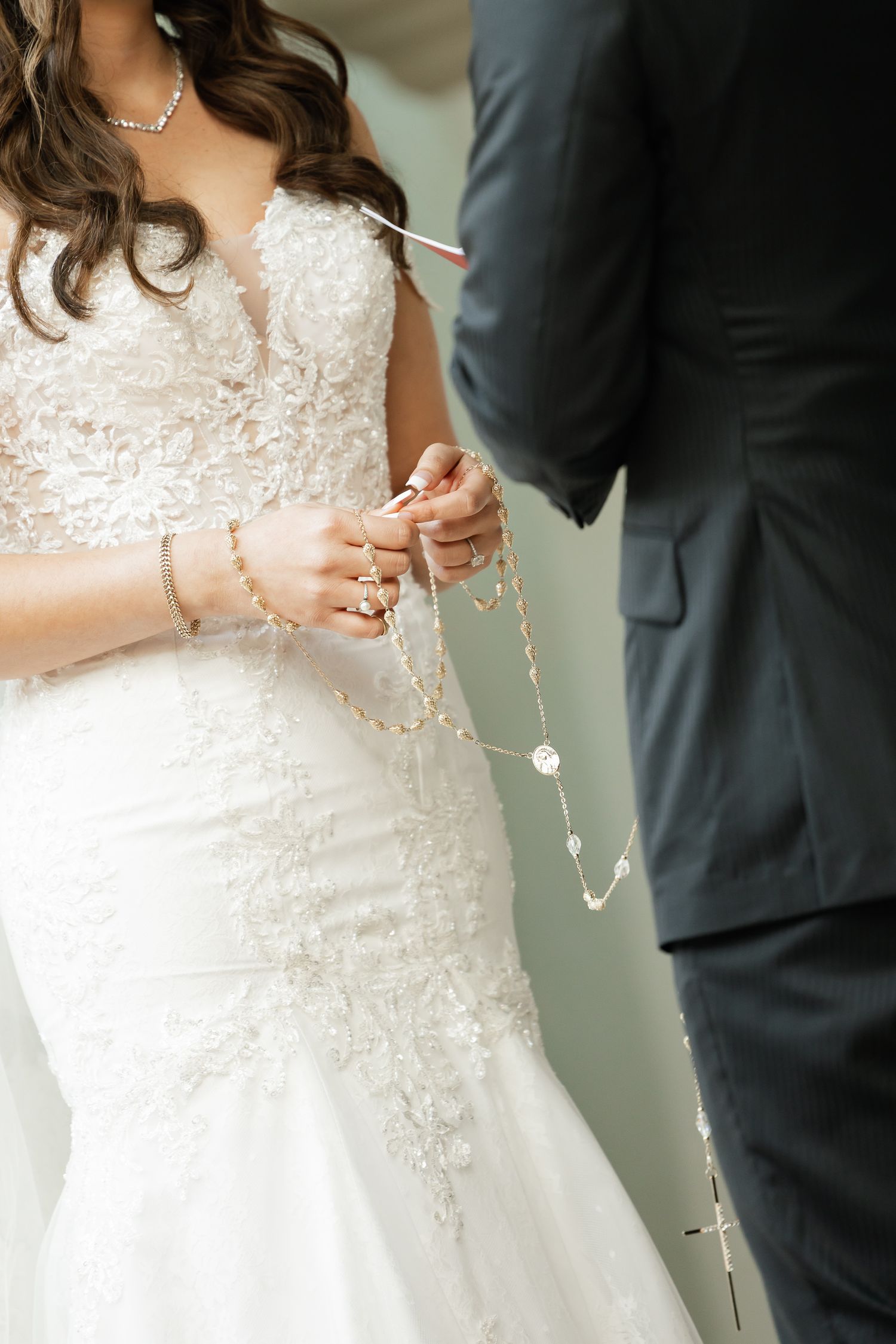 Close-up shot of a bride in a lace wedding dress and groom exchanging rings during wedding ceremony.
