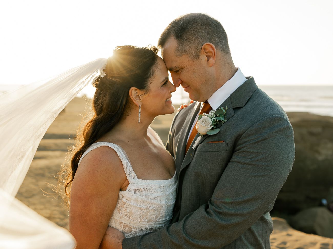 Intimate moment between newlyweds at sunset on scenic coastal overlook.