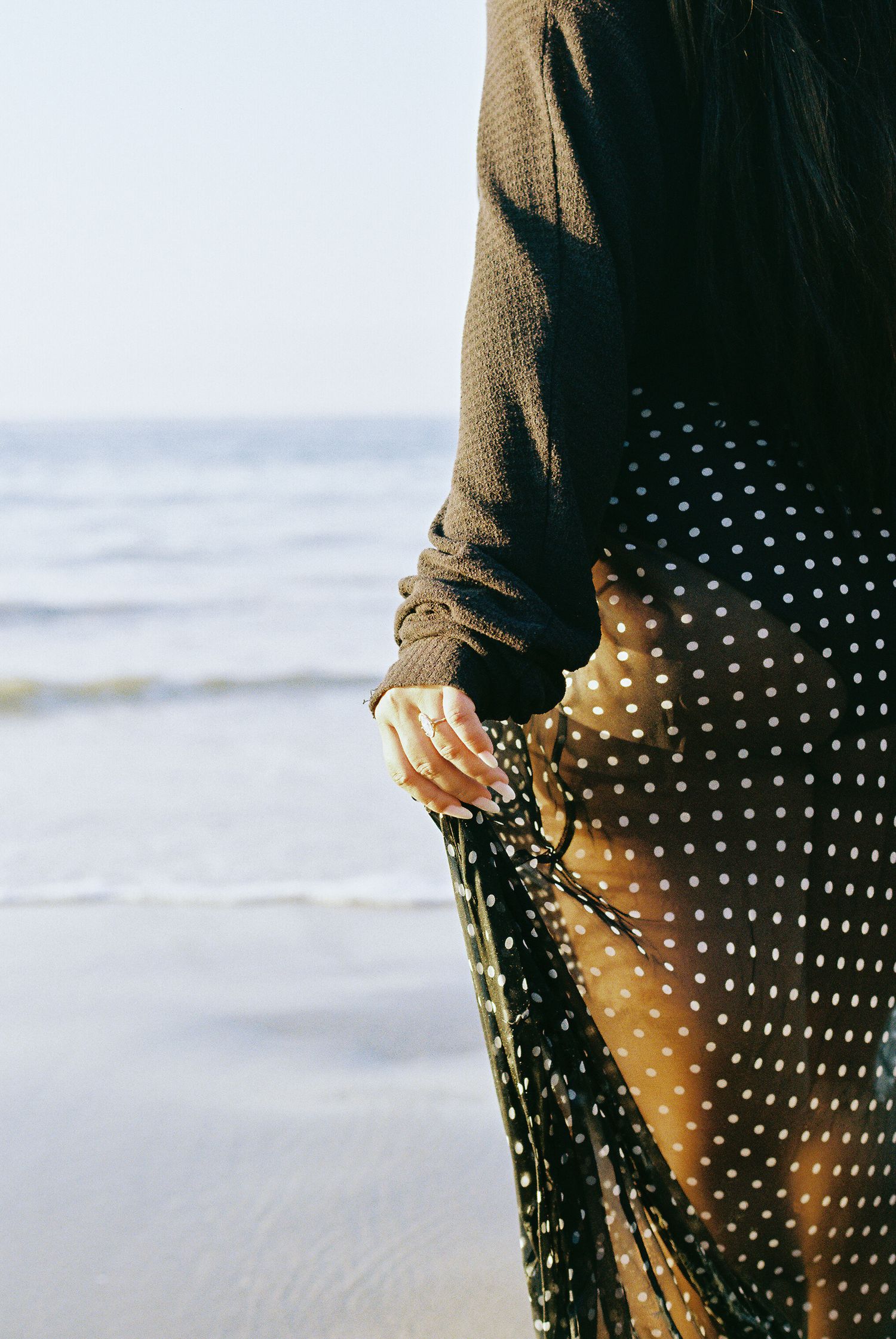 Close-up view of a polka dot dress and sweater against an ocean backdrop.