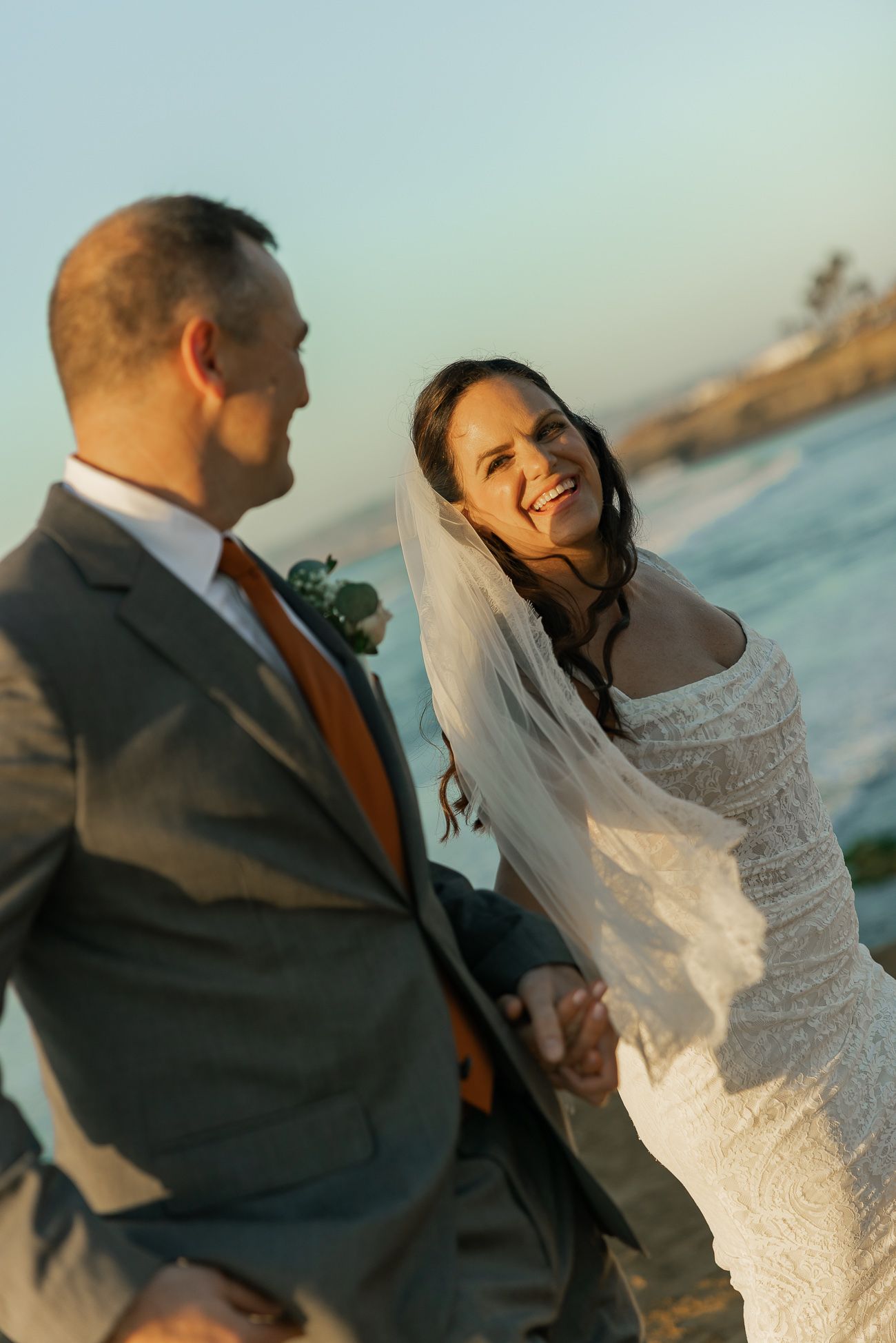 A couple shares a joyful moment during their sunset beach wedding ceremony.