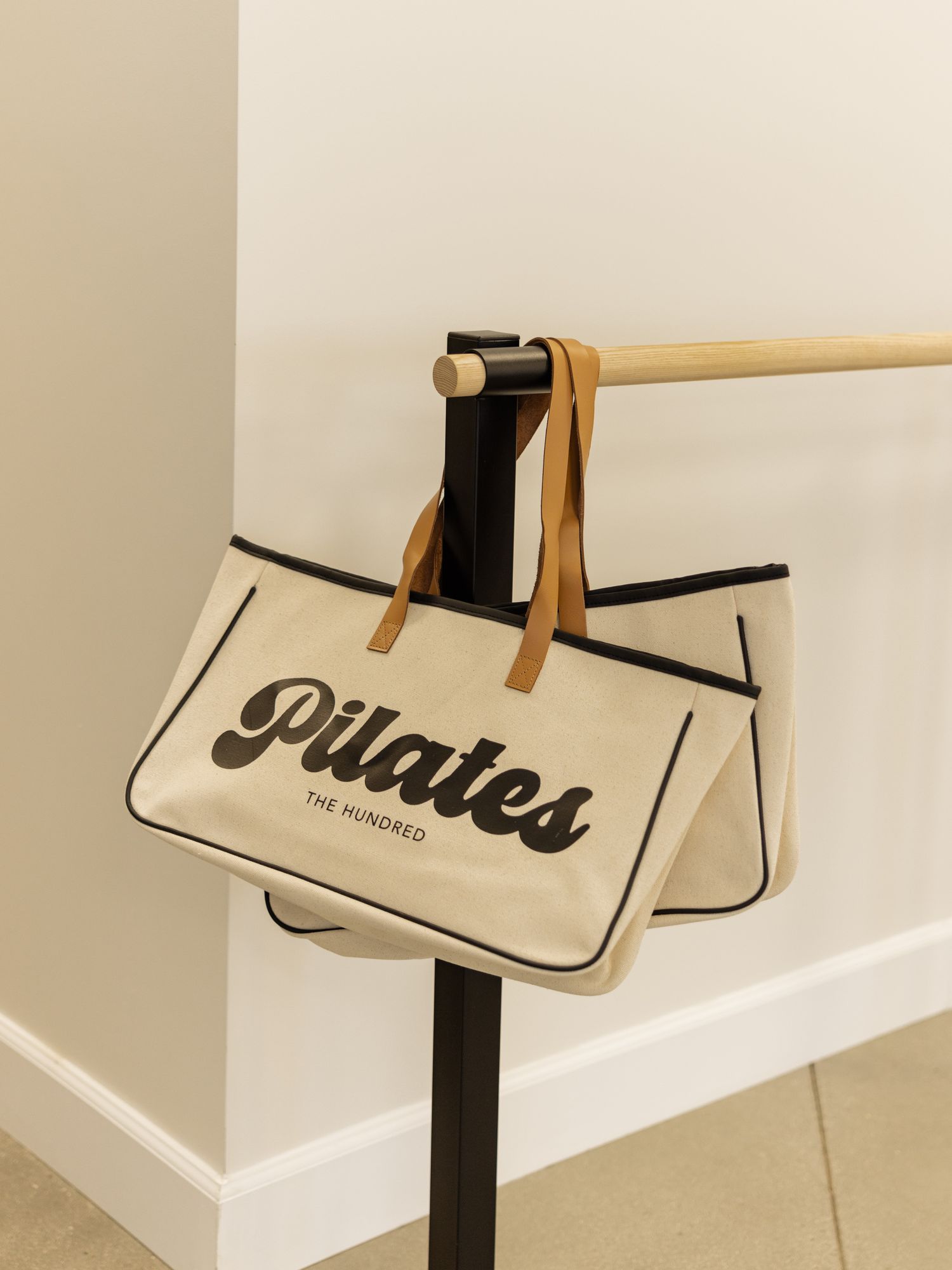 Wooden pilates equipment with beige canvas storage bags labeled with black text.