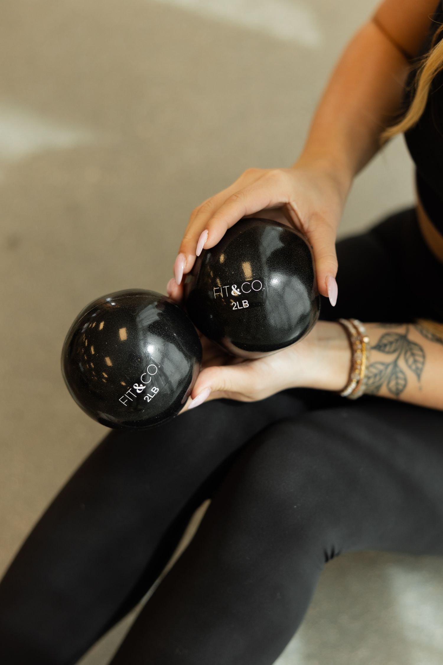 A black massage ball being rolled along a person's leg wearing black leggings to relieve muscle tension.