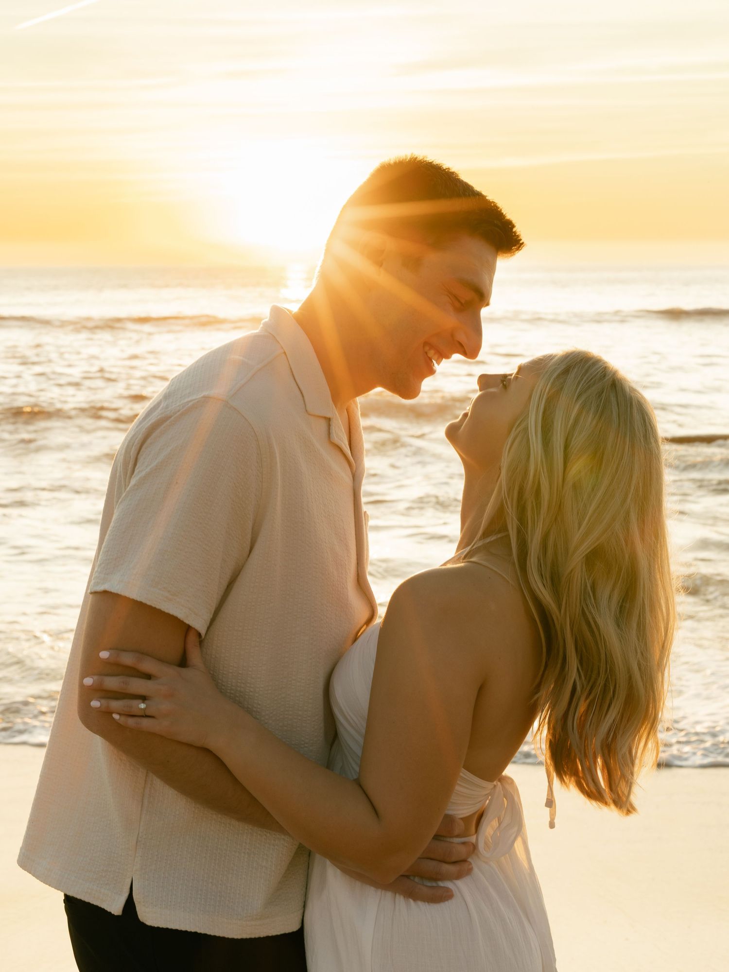Romantic beach portrait of couple embracing during golden hour sunset.
