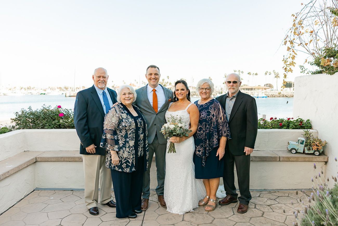 Wedding party gathered for formal portrait on oceanview terrace during sunset.