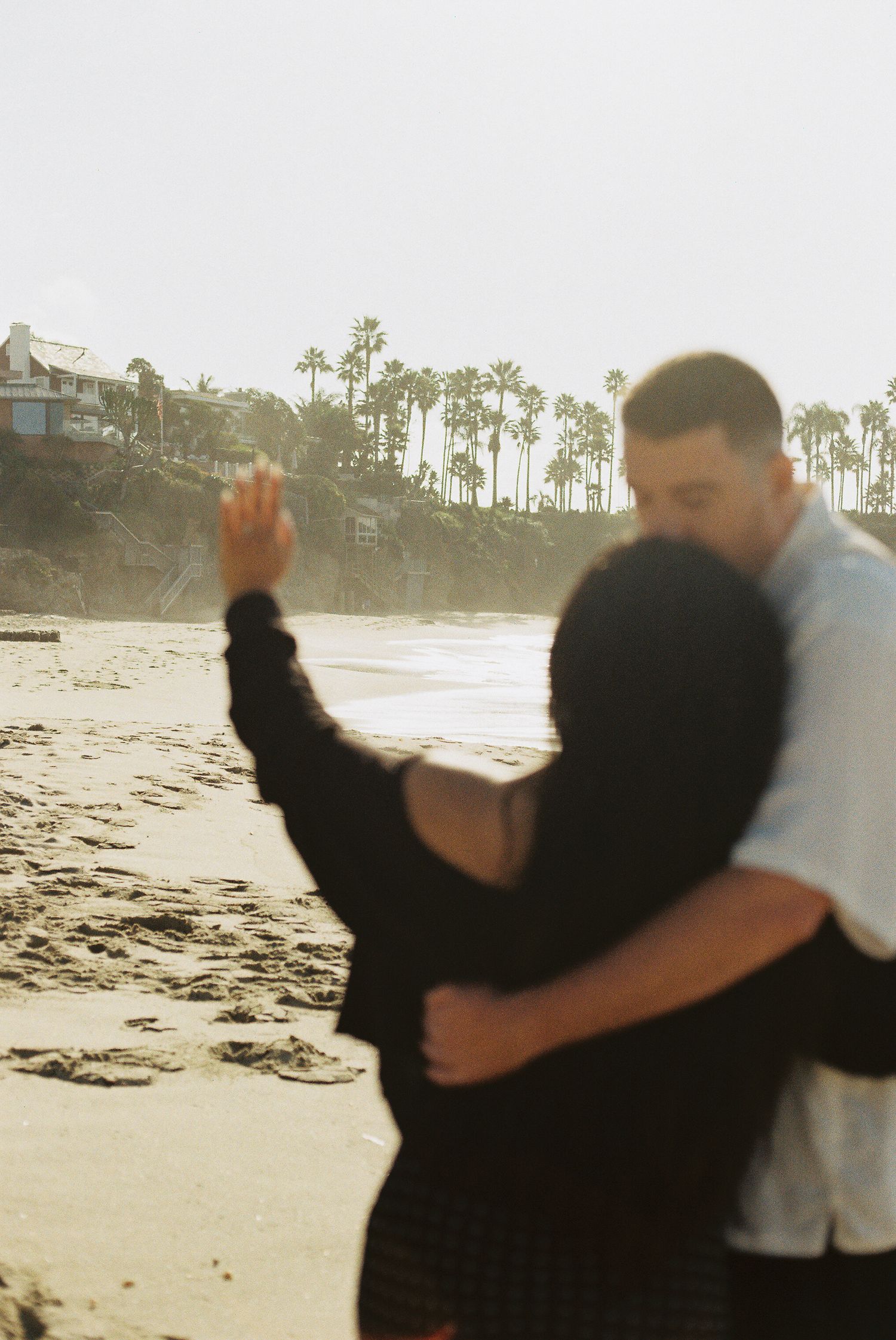 A sequence of silhouettes showing two people playfully interacting on a beach at sunset with palm trees in background.