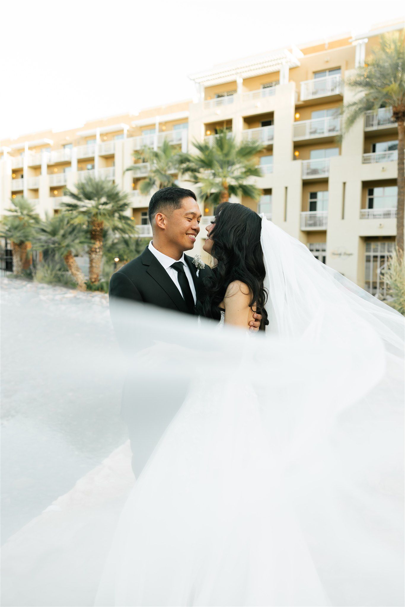 A couple shares an intimate moment with a flowing veil at a resort.