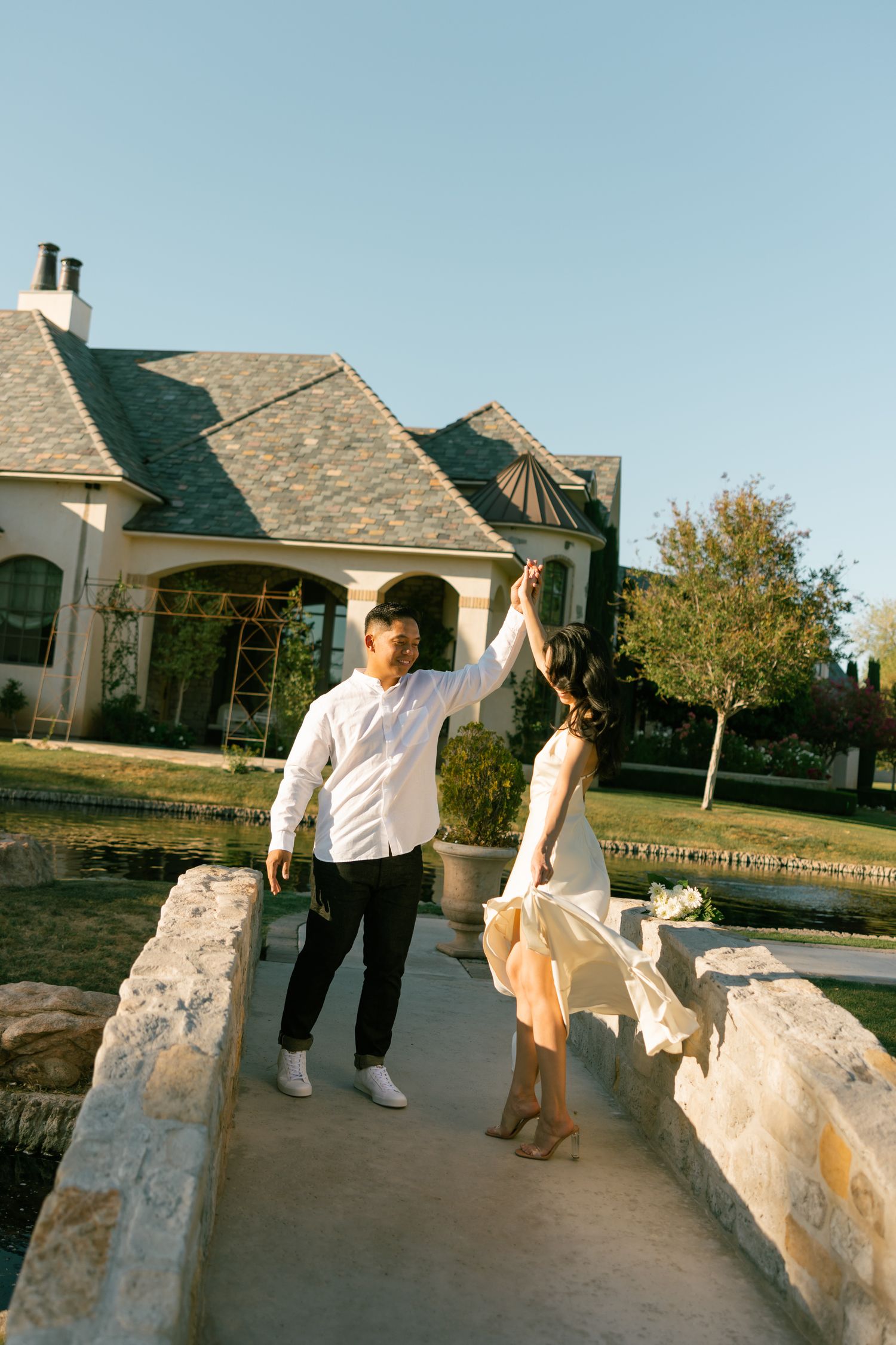 People walking and sitting on a concrete wall outside a residential building at sunset.