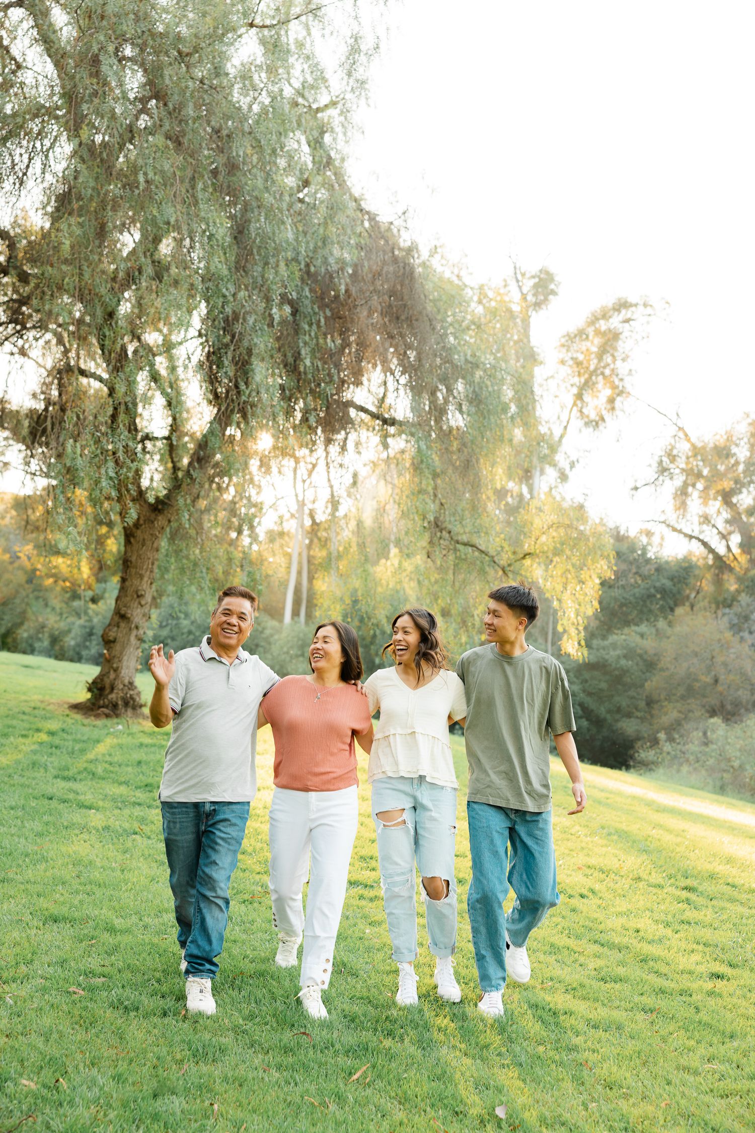 A group walks together on a grassy hillside during golden hour with trees in the background.