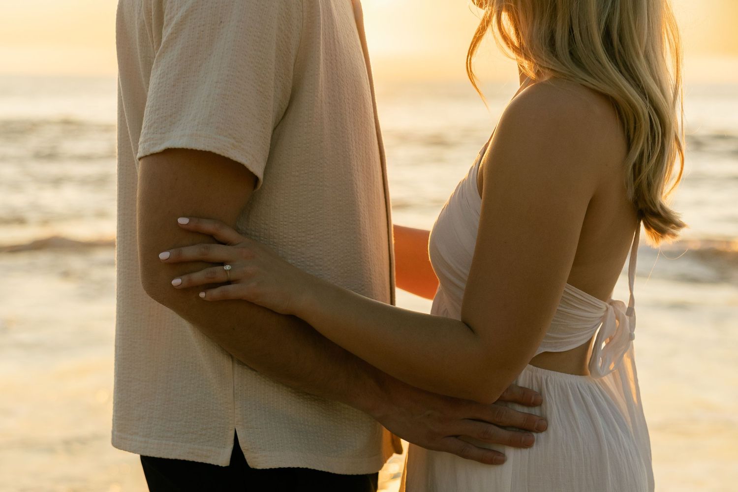 Close-up of couple embracing on beach during golden sunset.