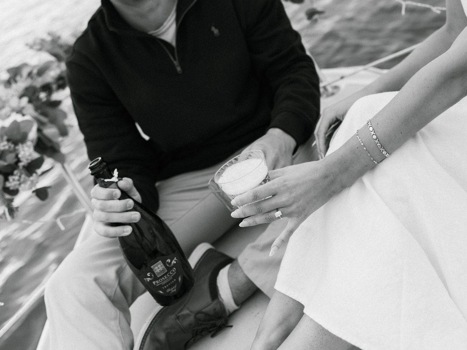 A couple holds hands during an intimate wedding ceremony moment, captured in black and white photography.