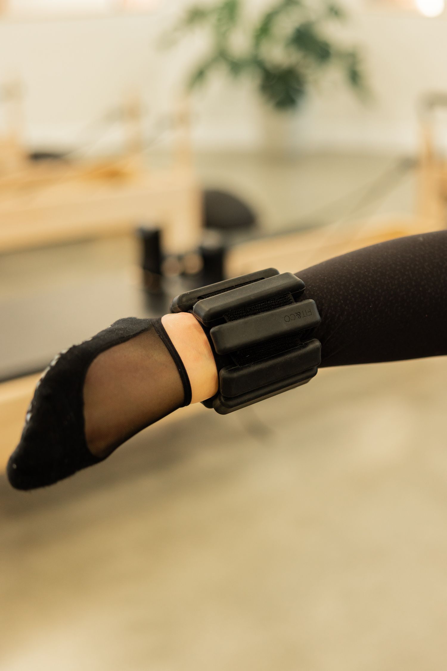 Close-up view of black padded foot straps on a Pilates reformer equipment.