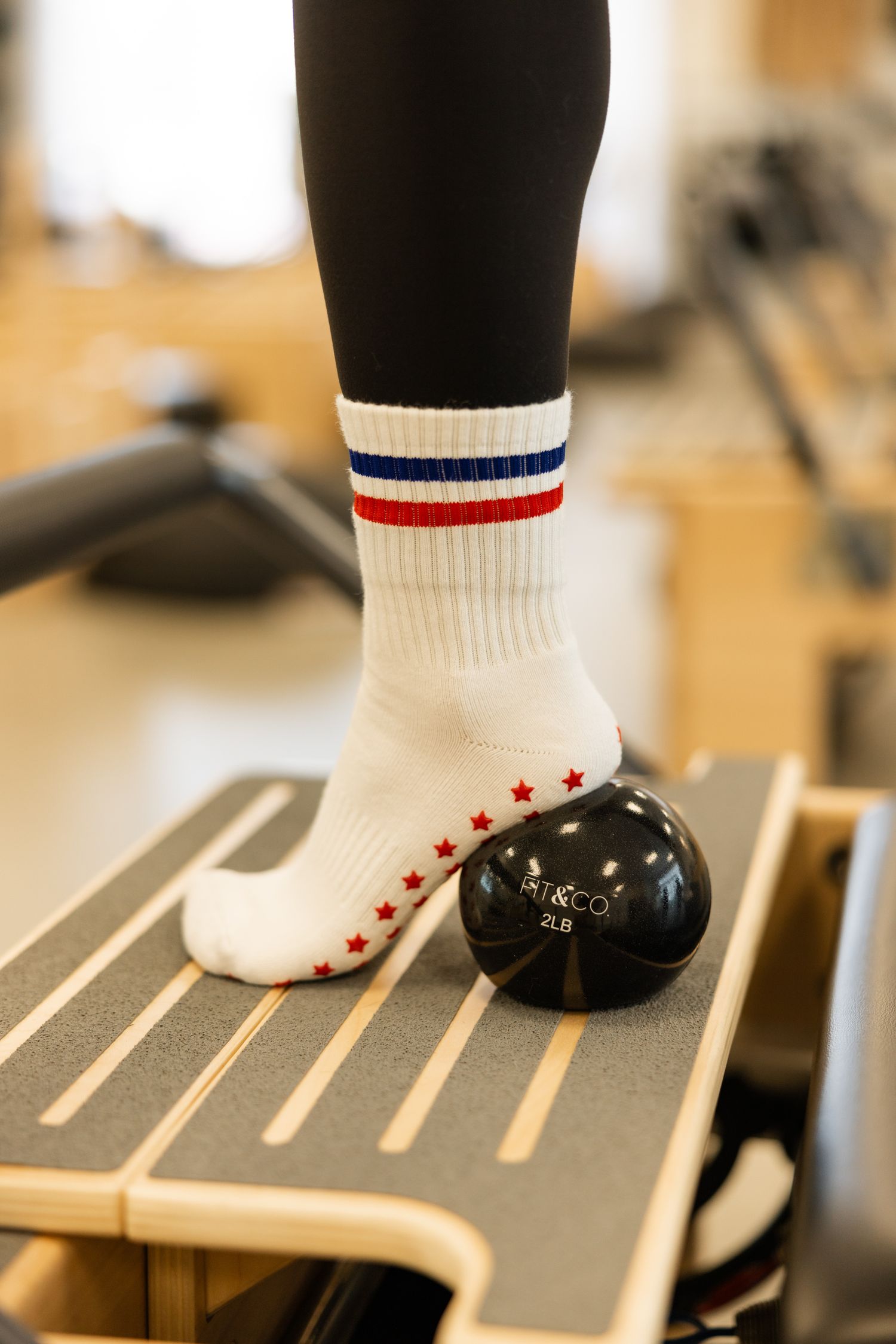 Close-up of feet wearing black ballet shoes and white socks with red stars performing dance steps on a wooden floor.