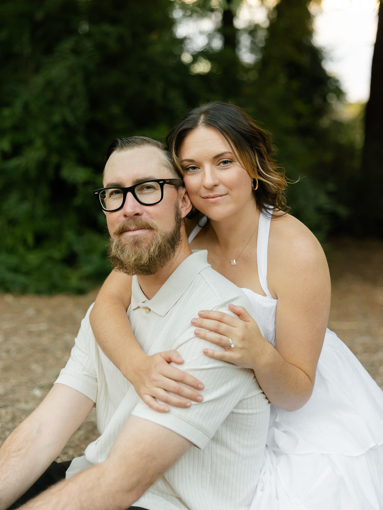 A tender embrace captured in a wooded setting with white summer outfits.