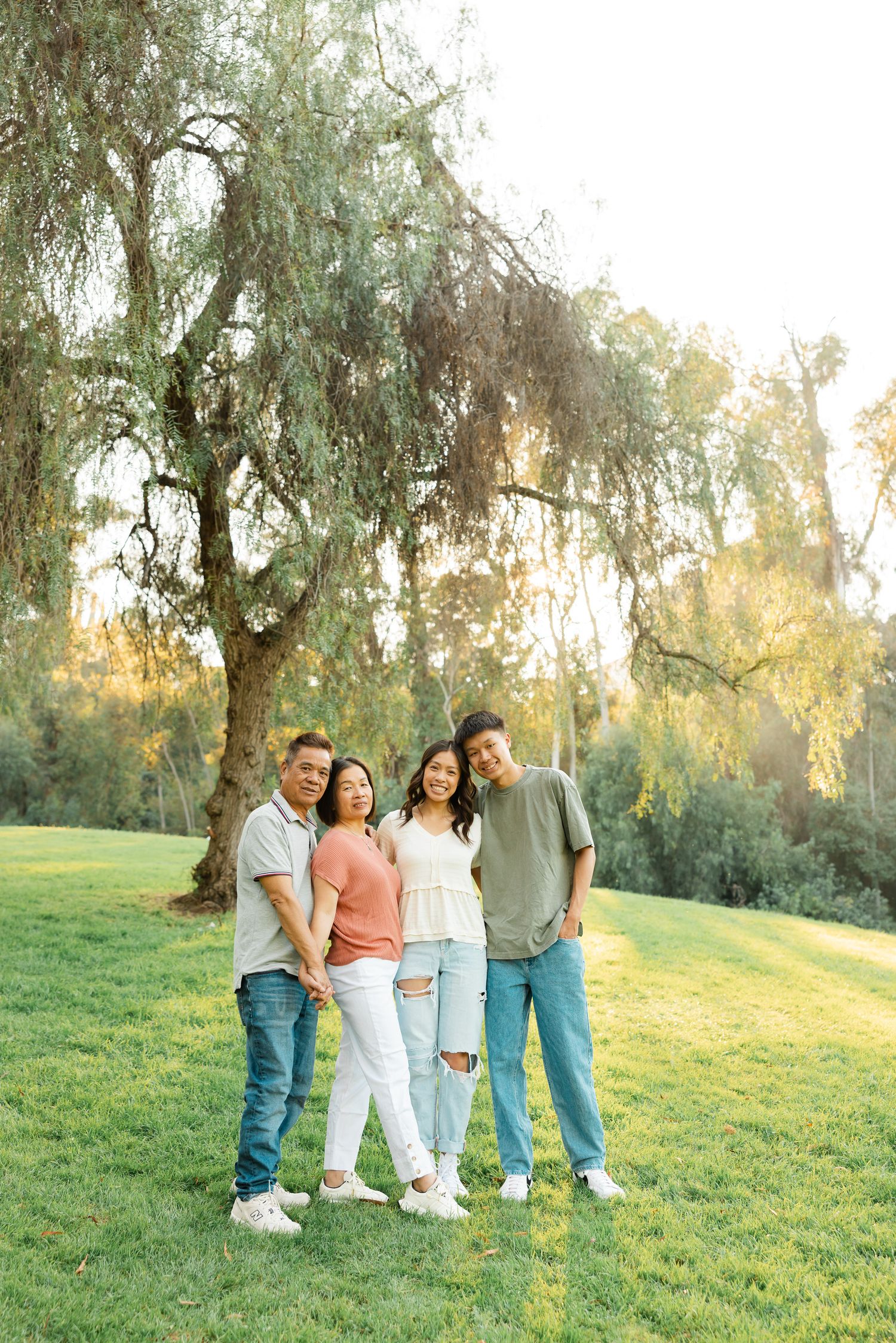 People share joyful moments together on a grassy slope during a warm sunset photoshoot.
