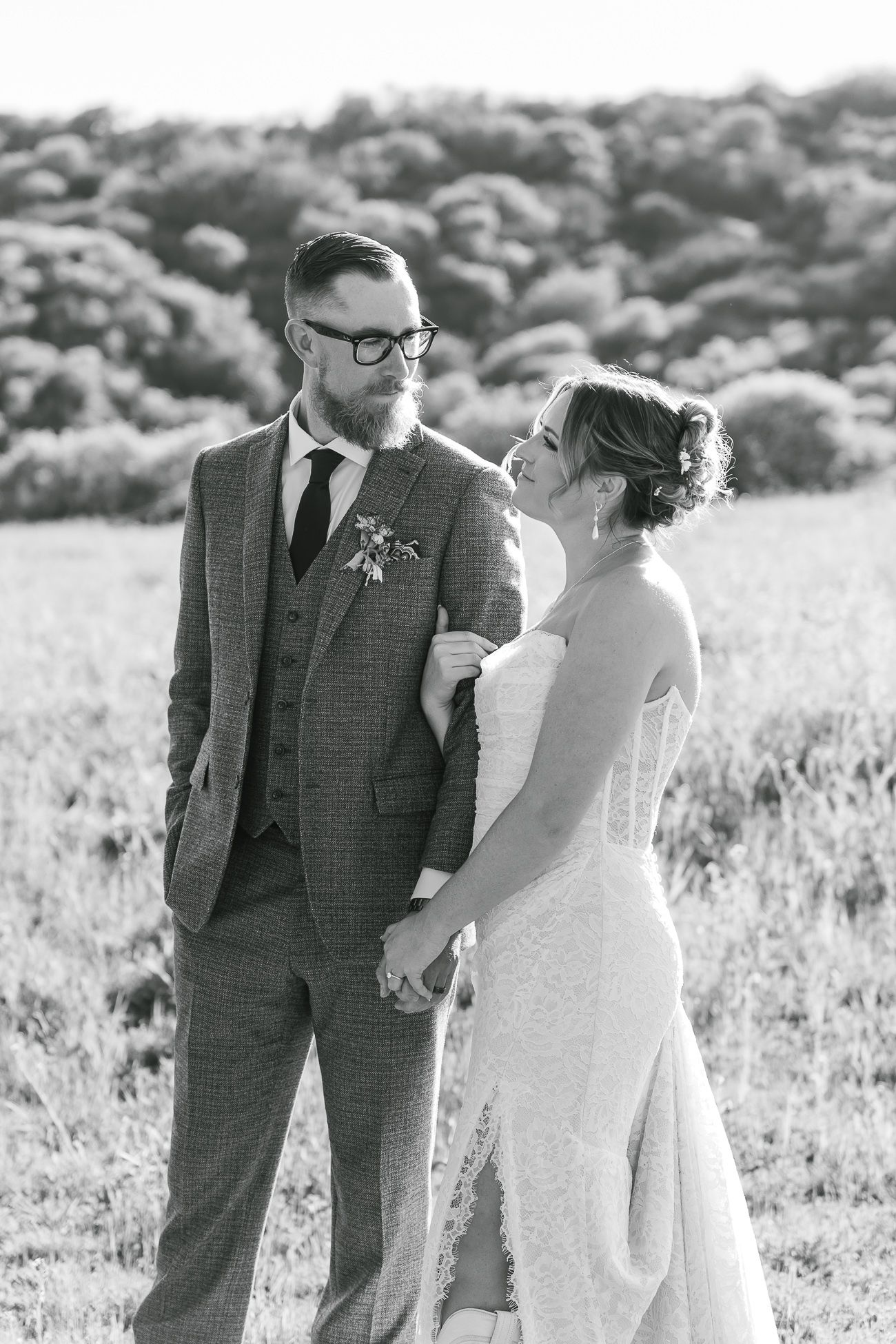 Black and white wedding photos of couple sharing intimate moments in an outdoor field setting.