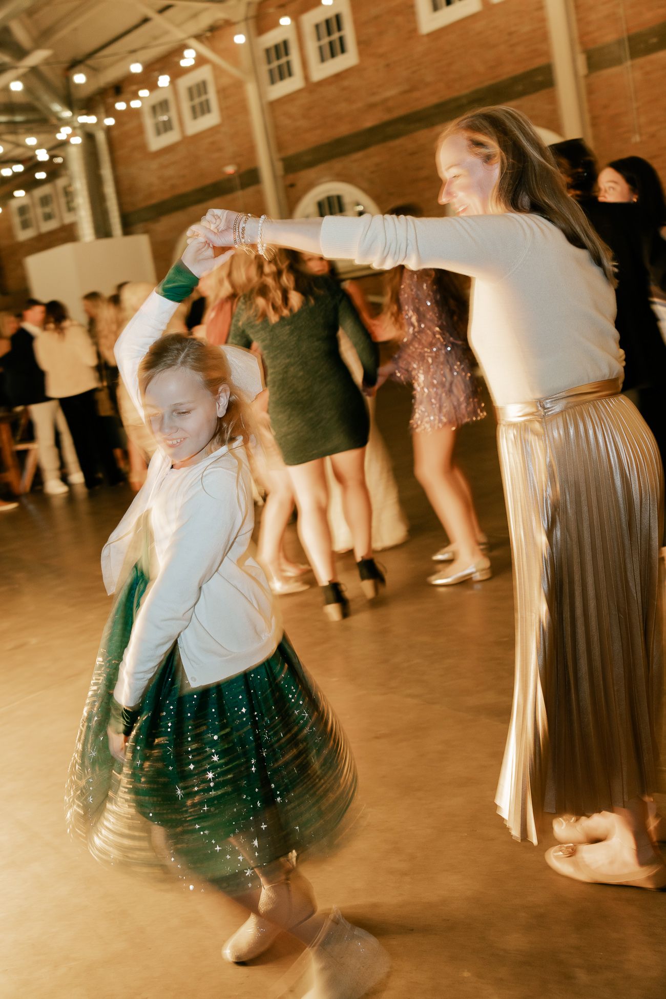 Wedding guests dancing joyfully on the reception floor under string lights.