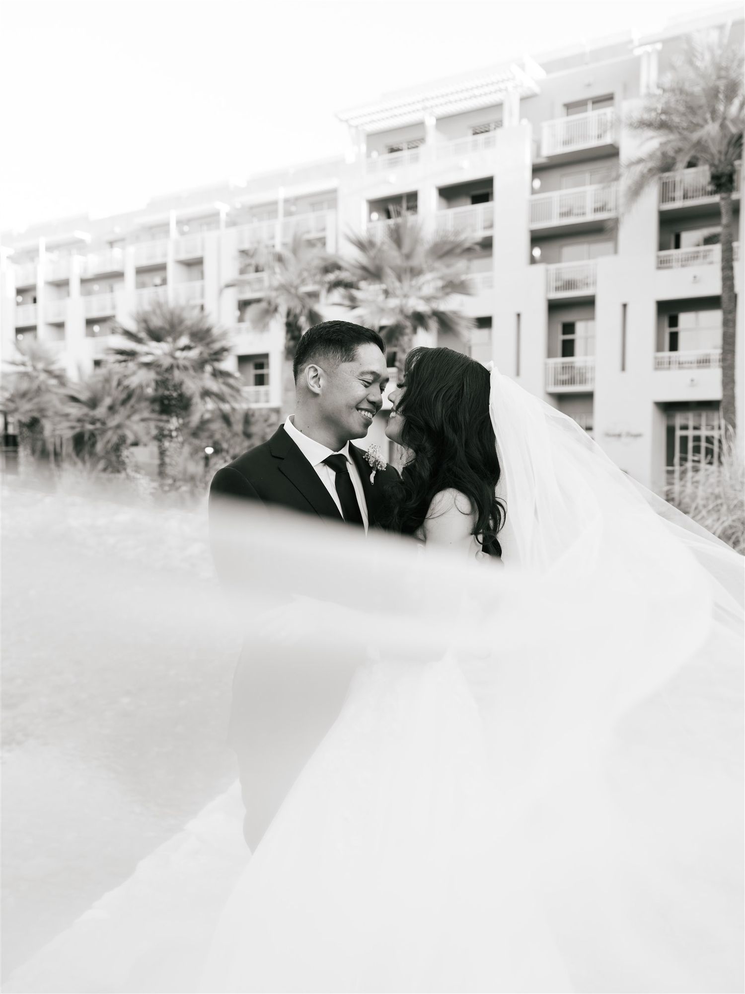 A romantic black and white portrait with palm trees and flowing veil.