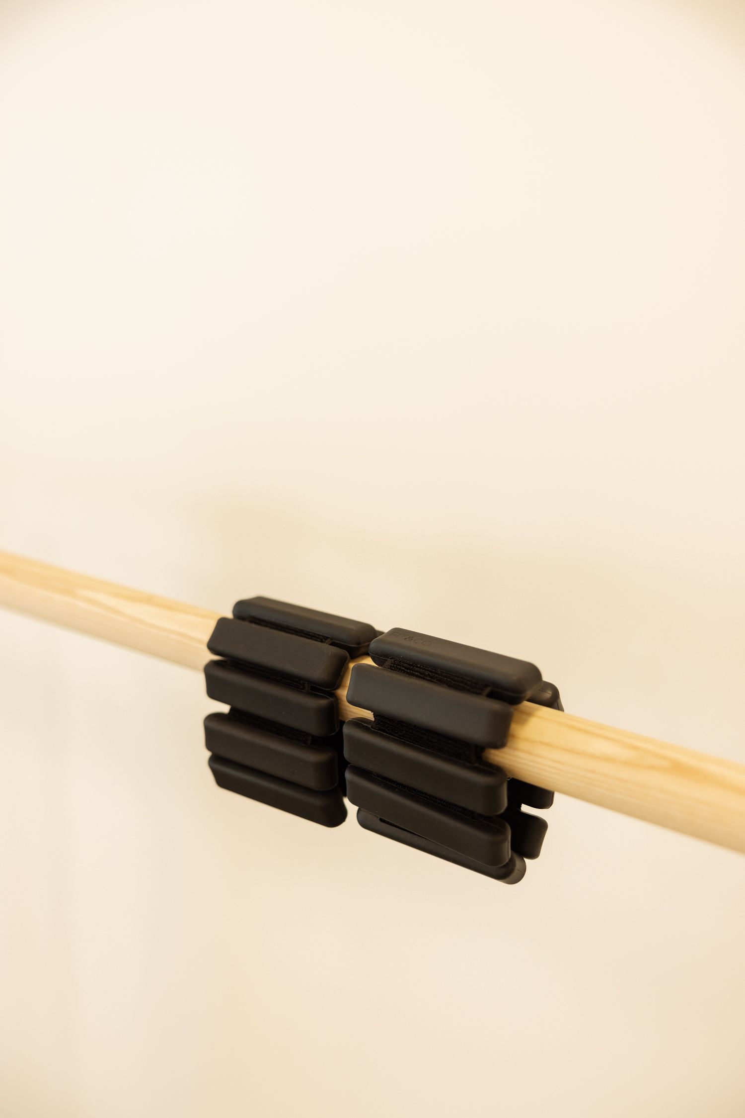 A sequence of photos showing a black plastic clip being attached to a wooden chopstick or dowel rod.