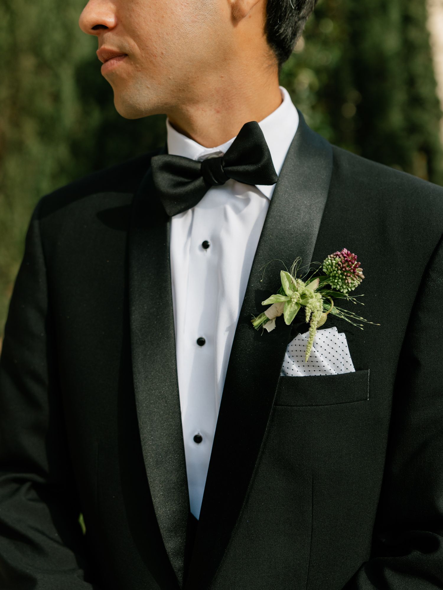 Close-up detail of a classic black tuxedo with bow tie and floral boutonniere.