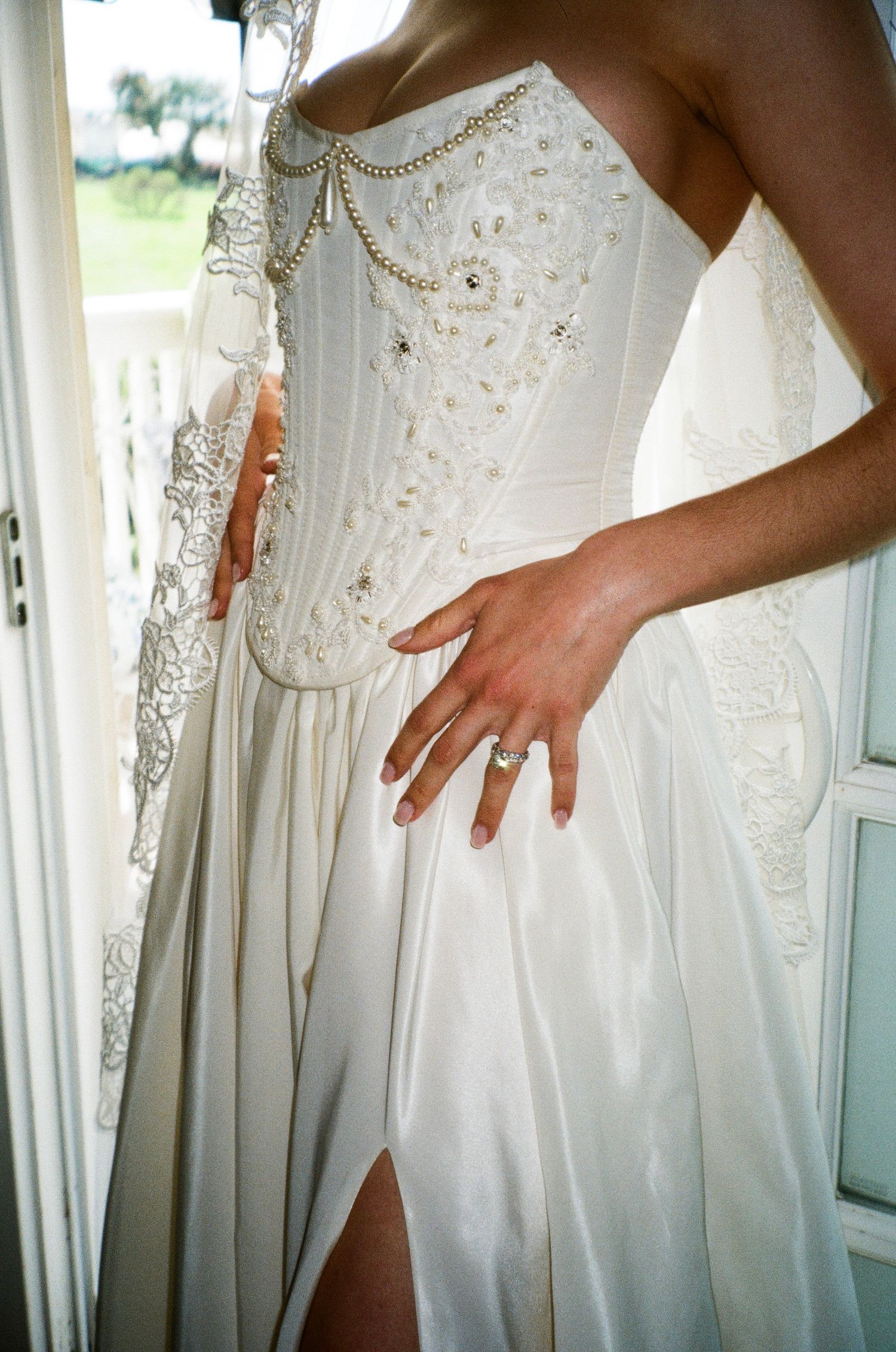 Close-up details of white wedding dresses showing delicate beading and lace embellishments on multiple gowns.