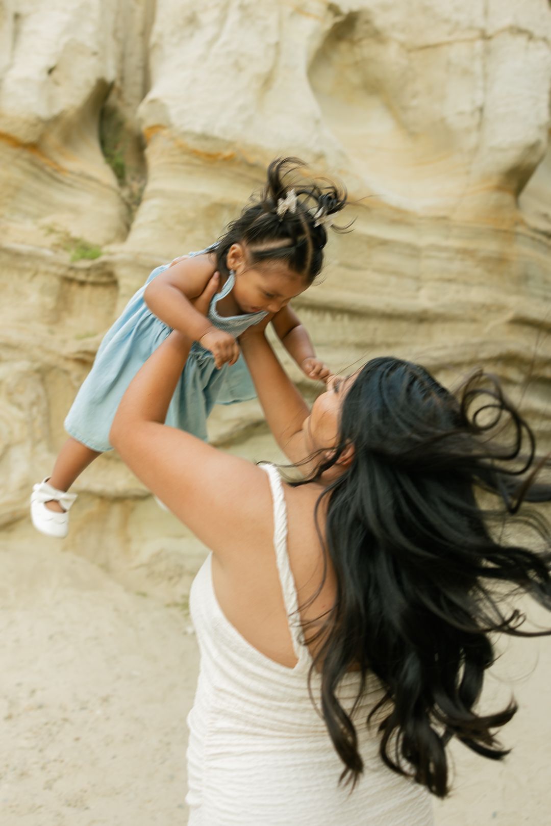A series of dynamic beach portraits showing a woman with flowing dark hair in a white dress against a sandy backdrop.