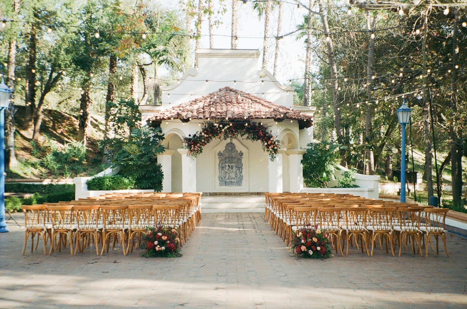 A panoramic view of an empty outdoor restaurant seating area with wooden chairs and tables under a covered patio.
