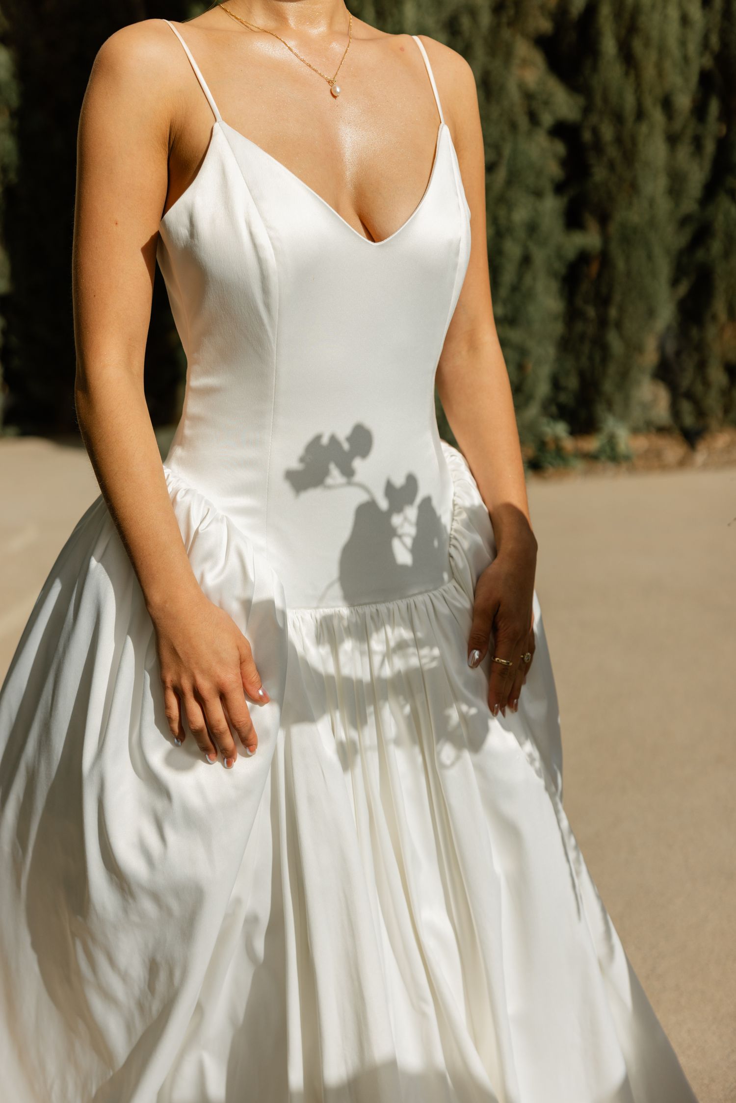 Close-up of a white satin wedding dress with dramatic shadows cast on the full skirt.