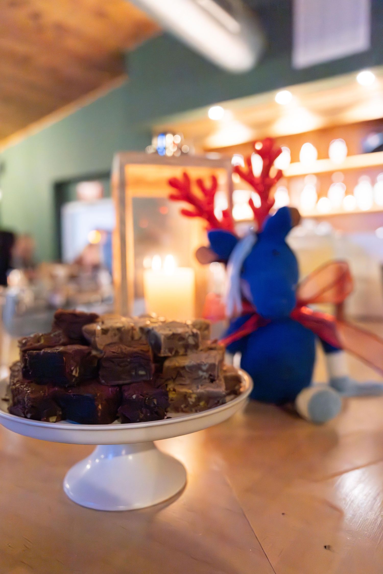 A plate of chocolate brownies on a white cake stand with a the Connecticut Morgan Horse Association stuffed animal mascot in the background.