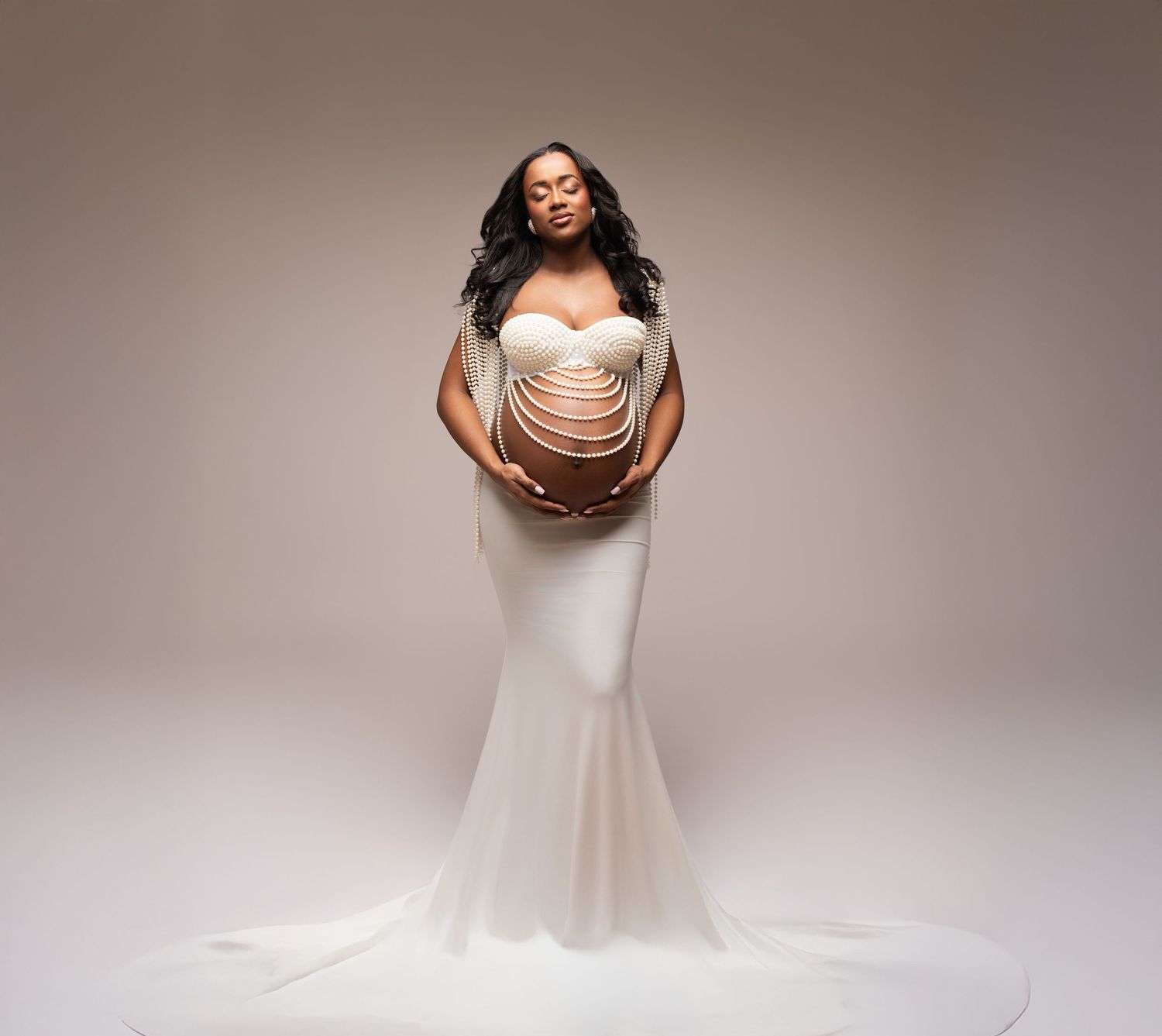 A person in a flowing white wedding dress twirls gracefully against a neutral studio backdrop.