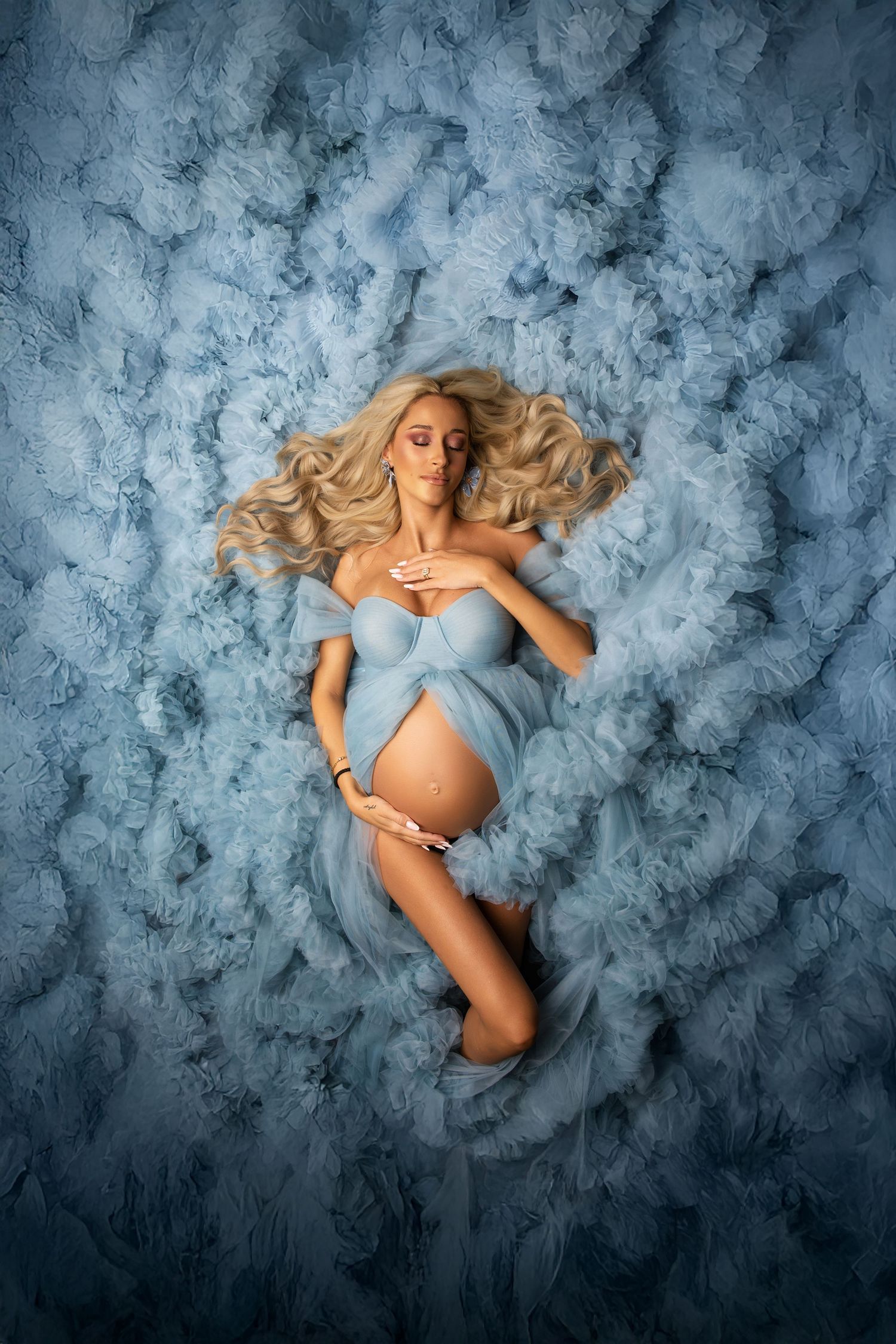 Artistic maternity portraits against blue textured backdrop show a pregnant woman in flowing ethereal poses.