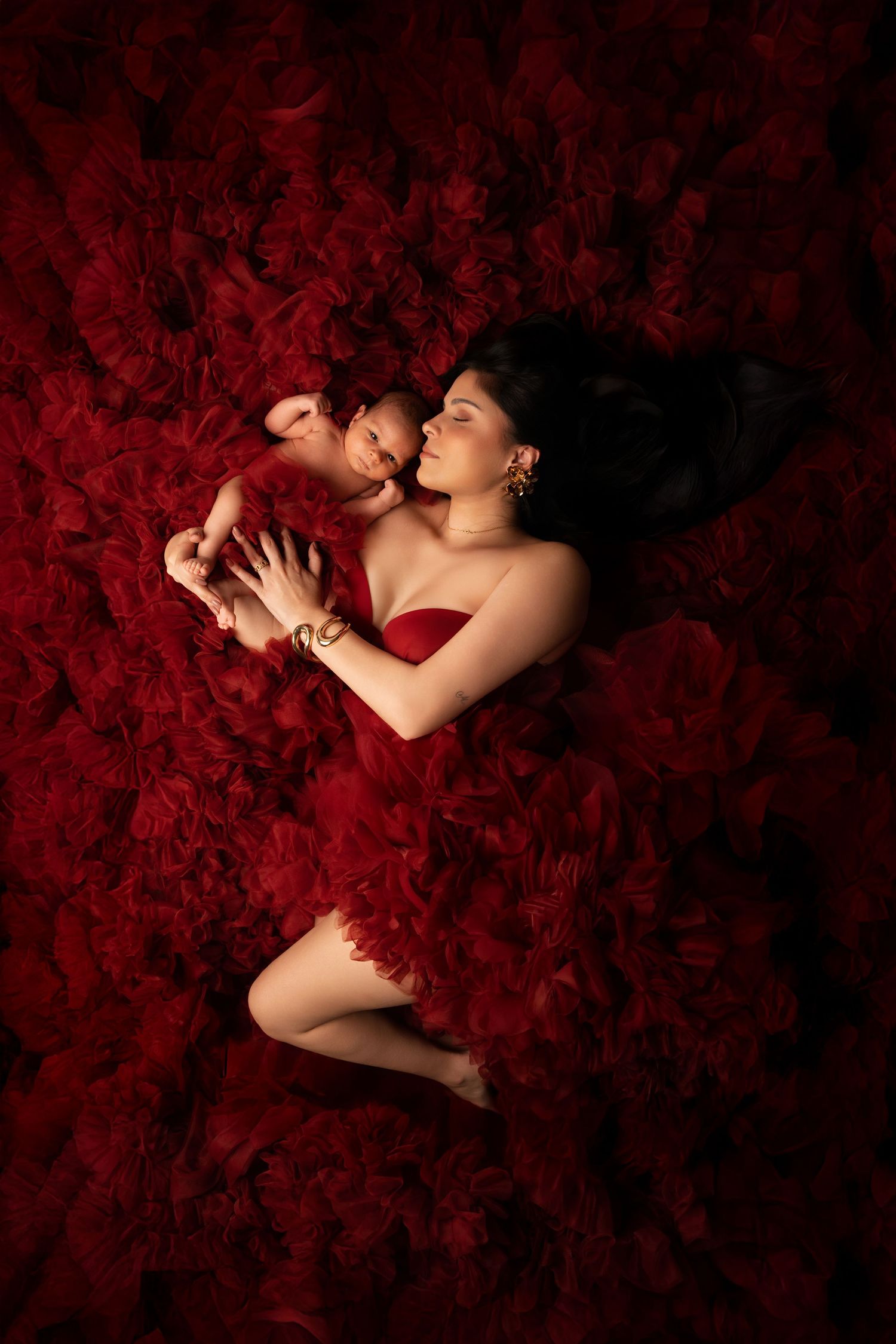 A romantic scene with red rose petals surrounding a couple in an intimate embrace against a dark background.