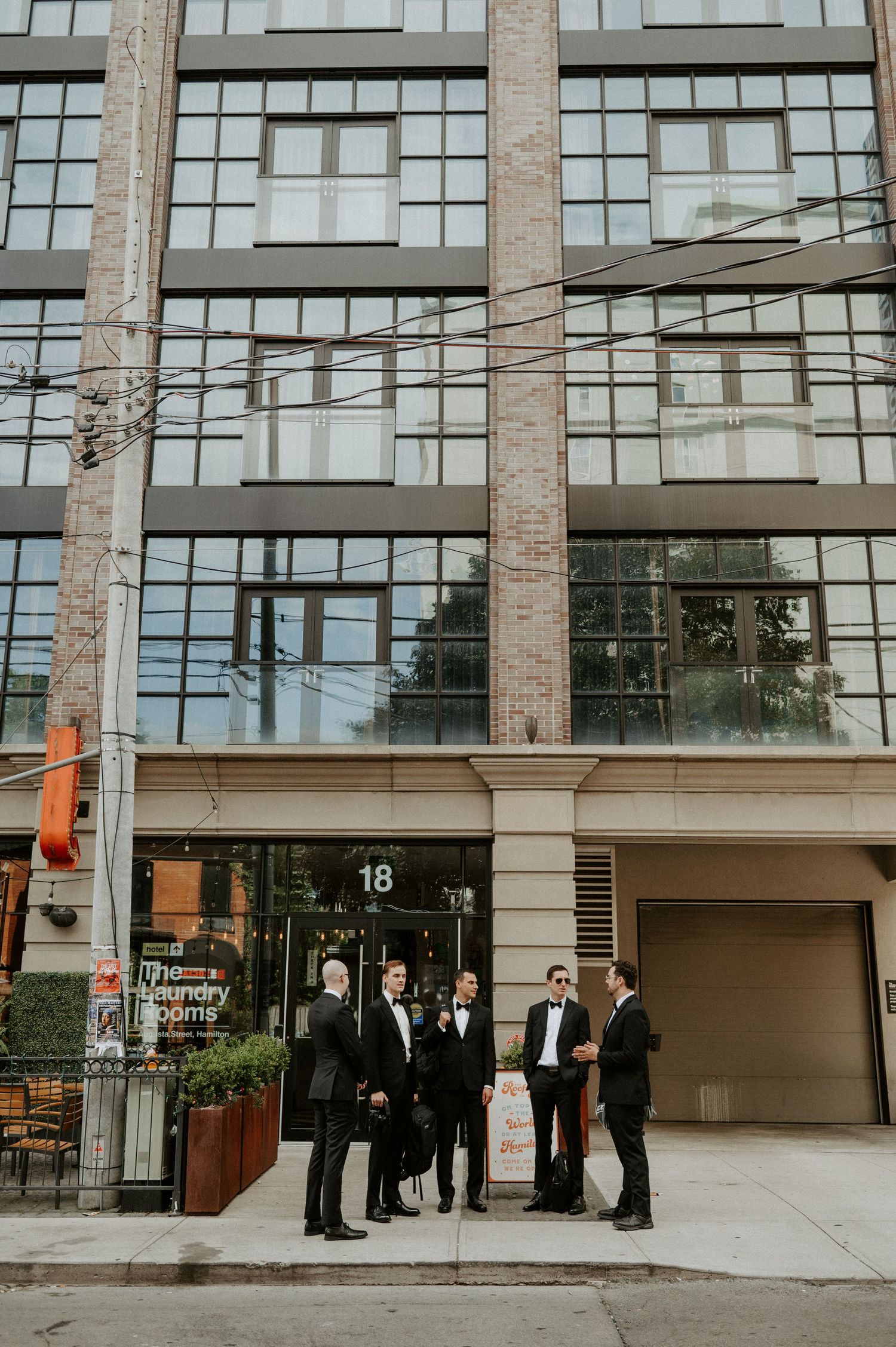 A group stands outside a modern brick and glass office building entrance on an urban street.