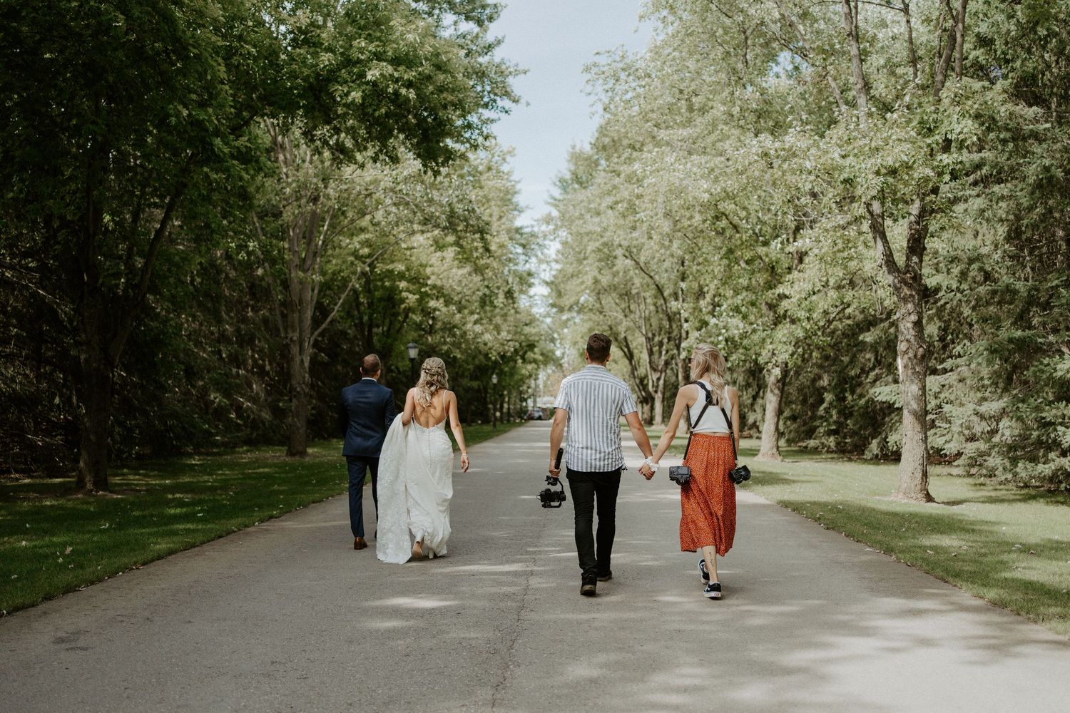 A couple walking on their wedding day followed by their photographers