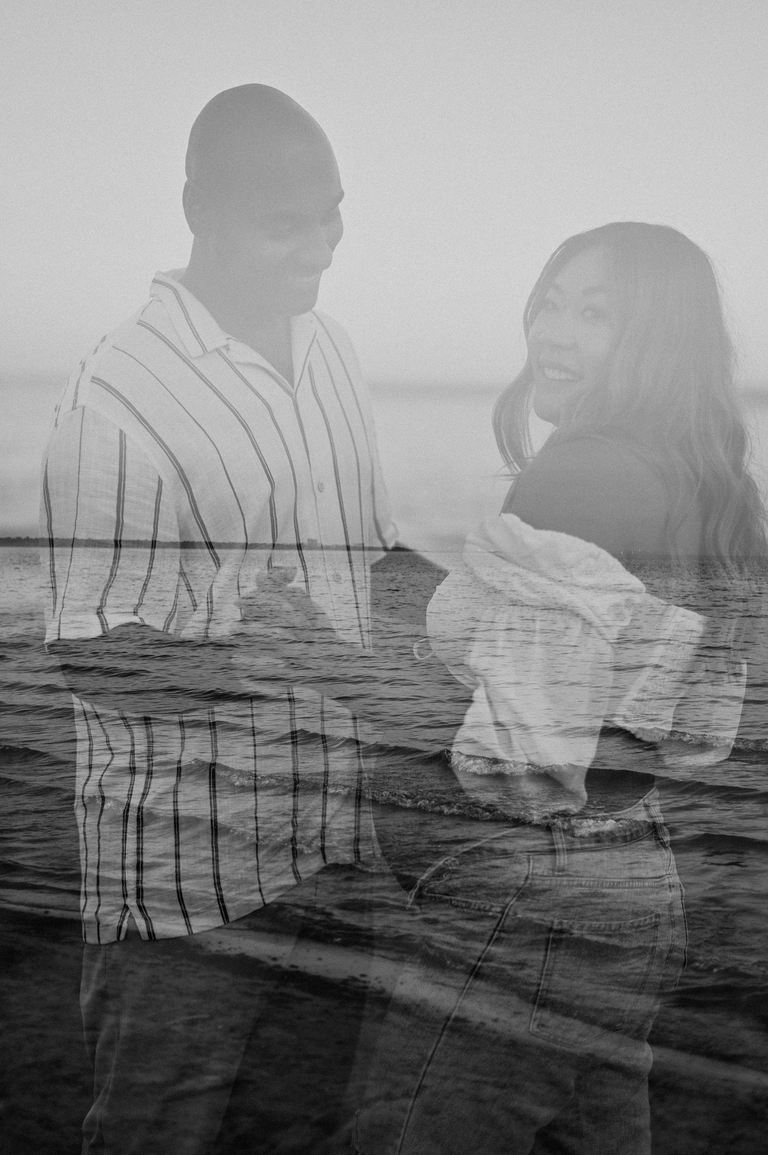 Double exposure black and white photo overlaying a romantic couple with ocean waves creating a dreamy effect.
