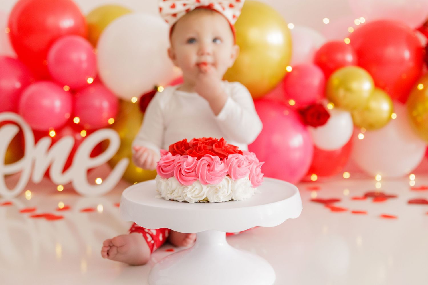 Valentine's themed first birthday setup with heart decorations and balloon arch.