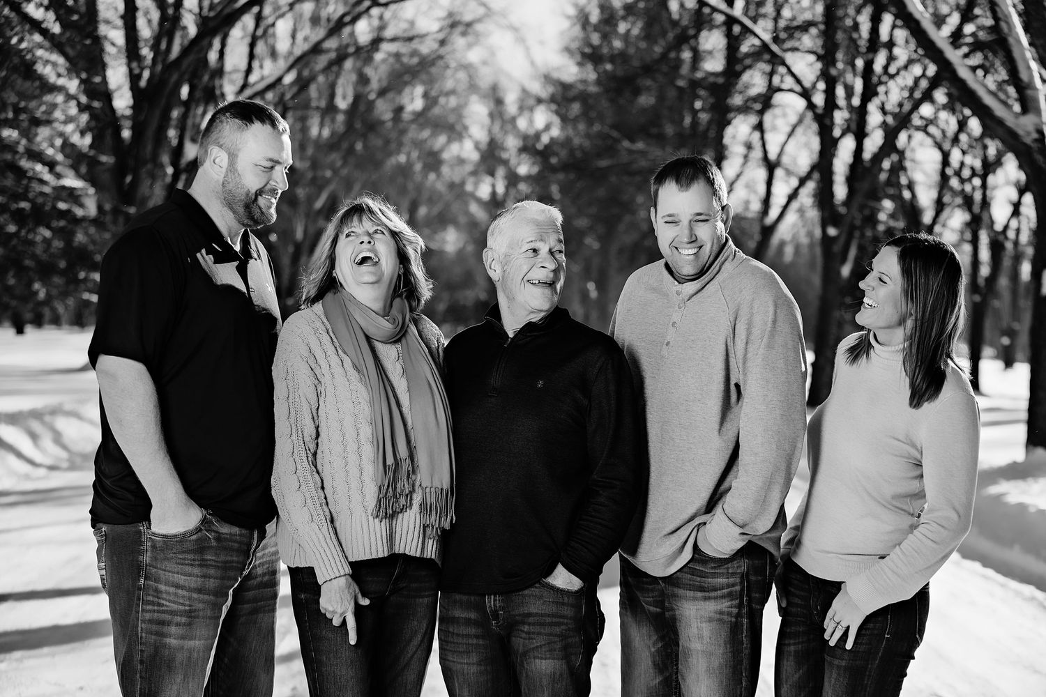 Five people share a candid laughing moment together during a winter photo session.