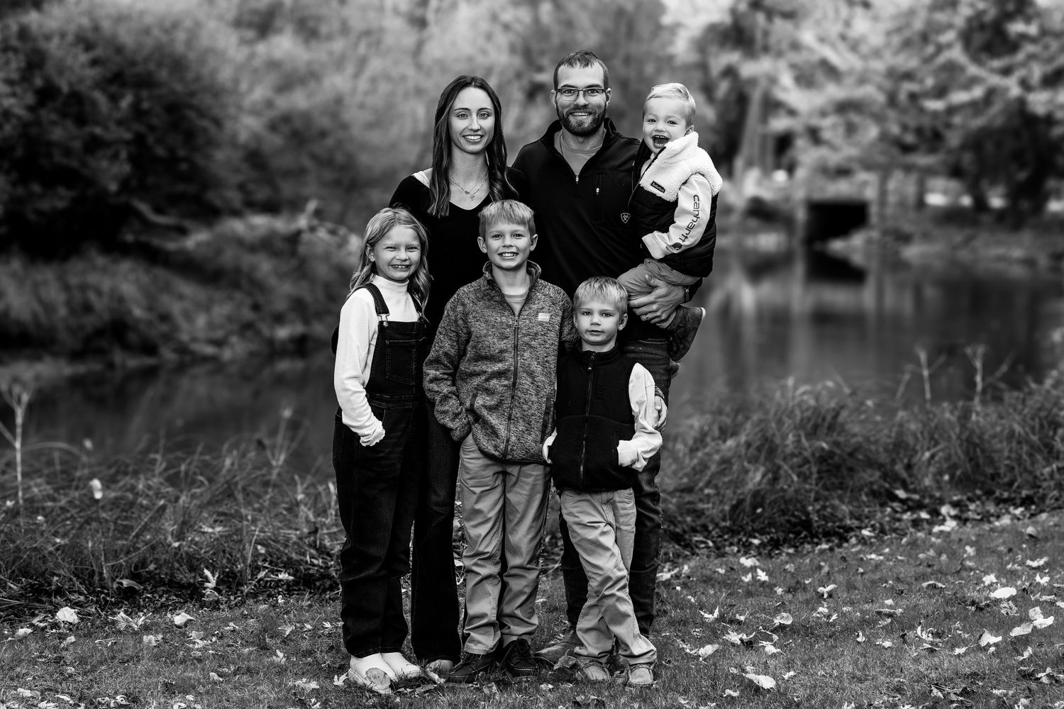 Family group portrait in casual attire against autumn landscape background.