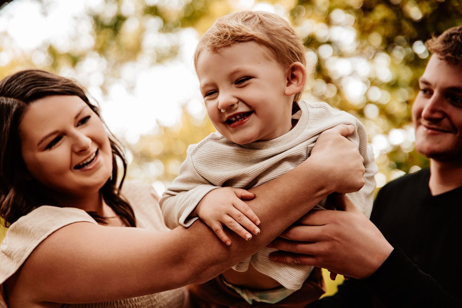 Candid family moment captured in warm sepia tones during an outdoor photoshoot.
