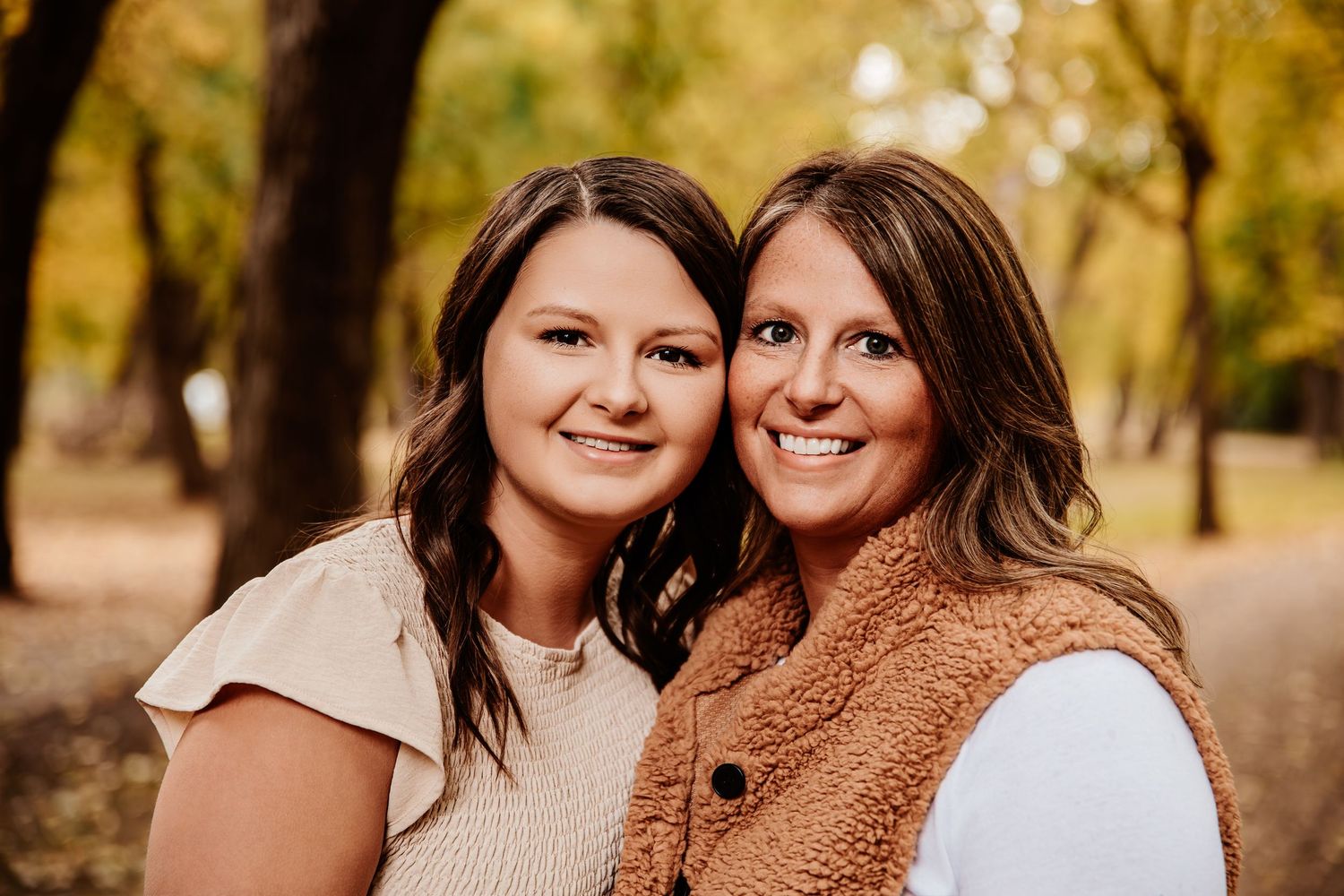 Two people share warm smiles while posing together outdoors.