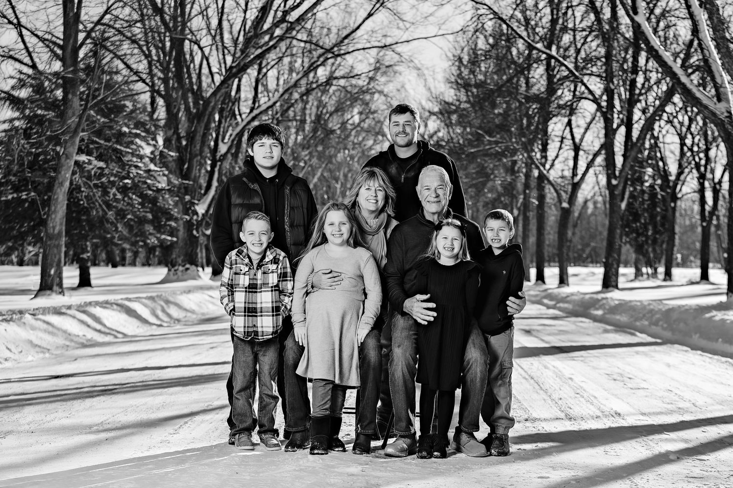 Black and white portrait of a small family group standing together in a snowy winter landscape.