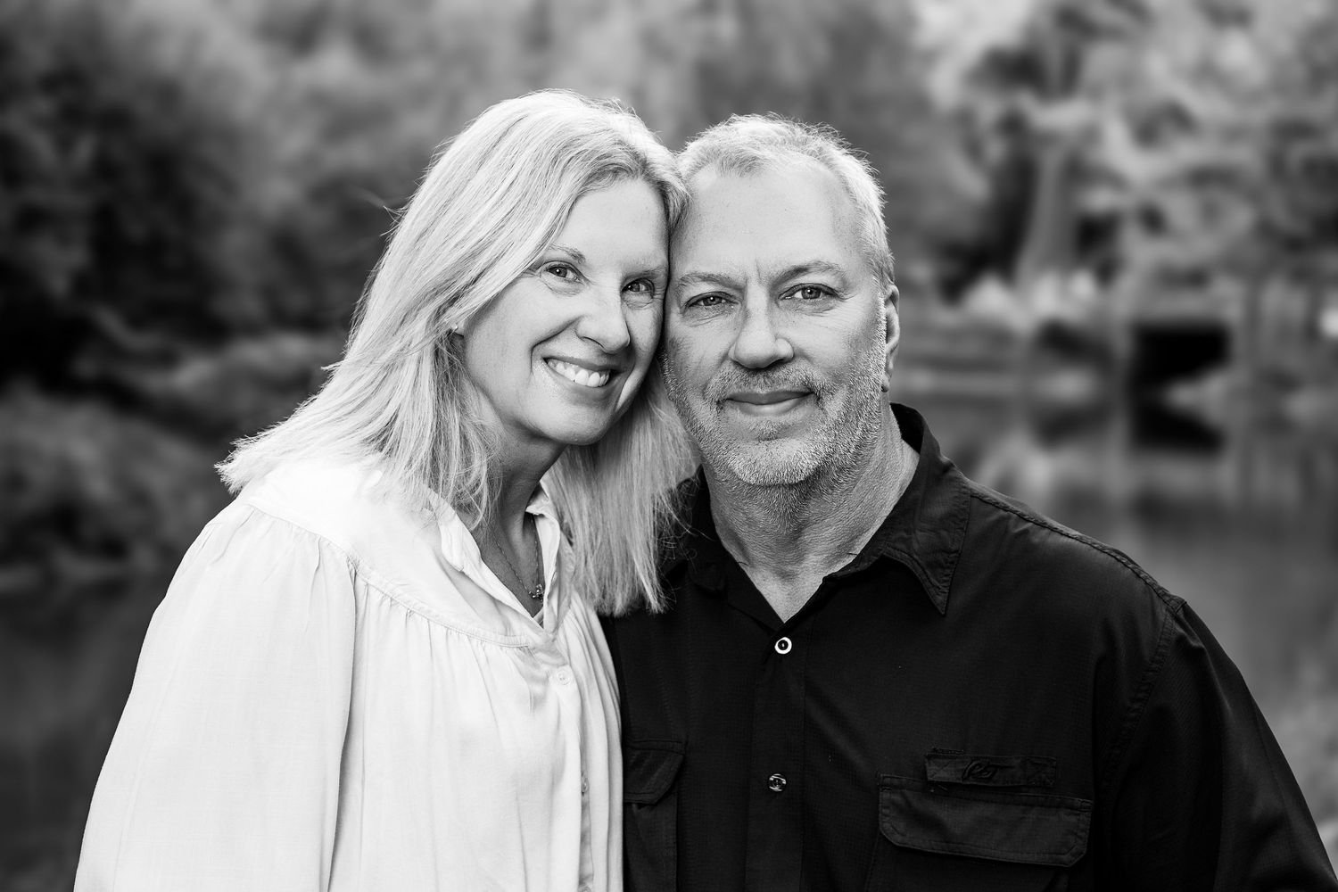 Black and white portrait of a couple embracing outdoors in intimate pose.