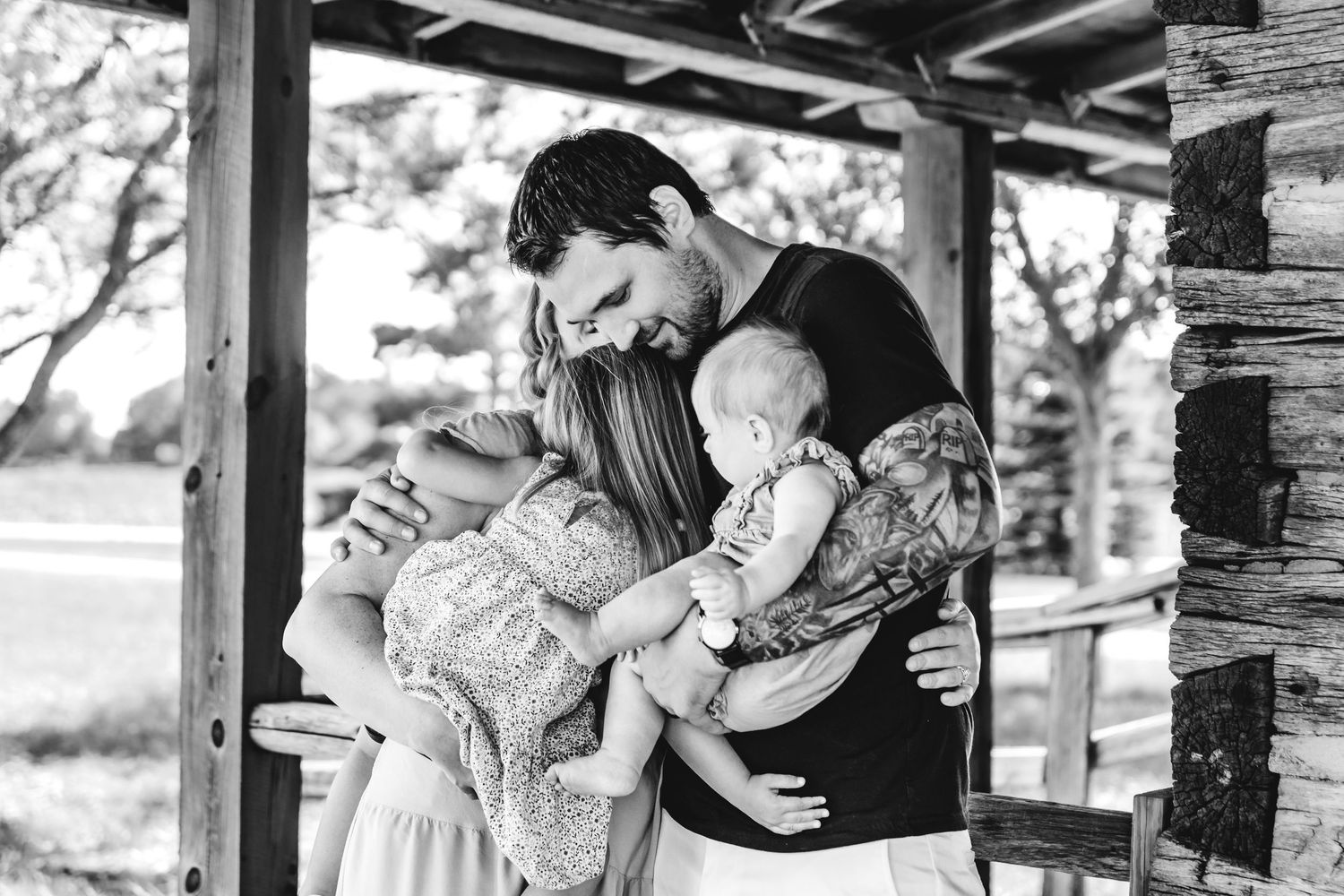 A tender black and white family moment captured on a rustic porch, showing affection and closeness between loved ones.