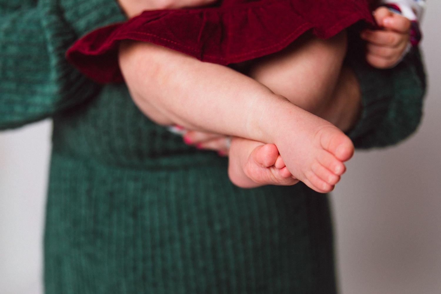 Close-up view of tiny baby feet against a green knitted background.