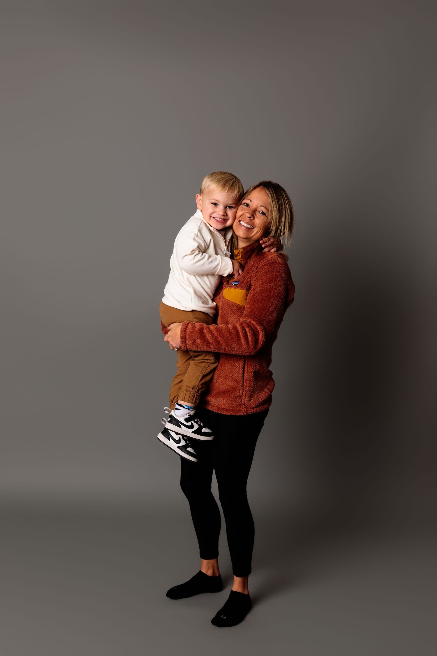 Series of loving embraces between parent and child against grey studio backdrop.