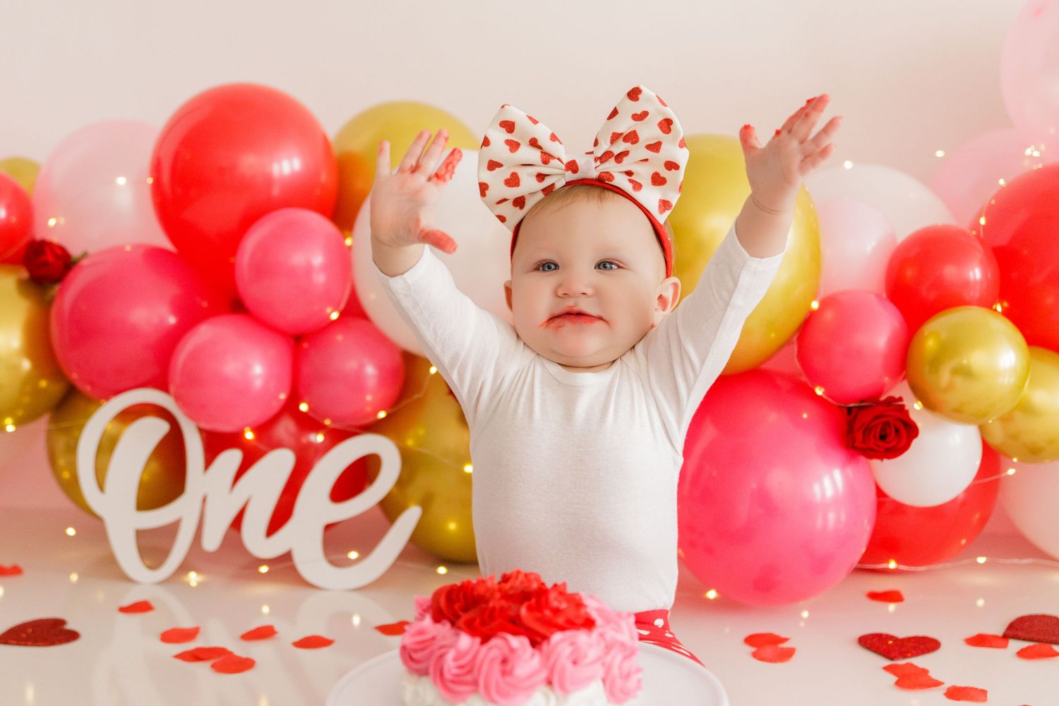 Pink and gold balloon backdrop with 'one' text decoration for first birthday celebration.