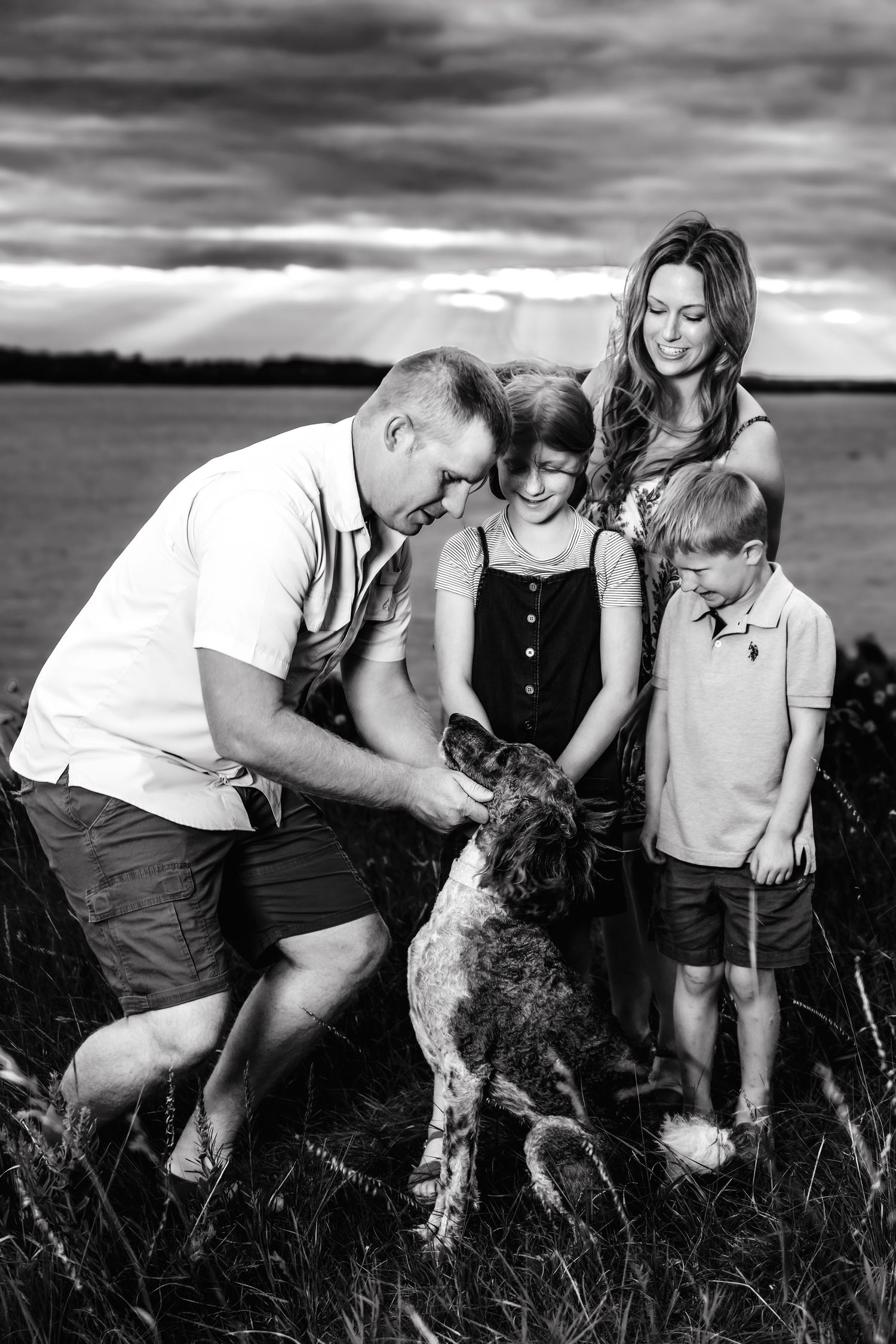 A black and white photo sequence shows several people crouching together in a grassy field at sunset.