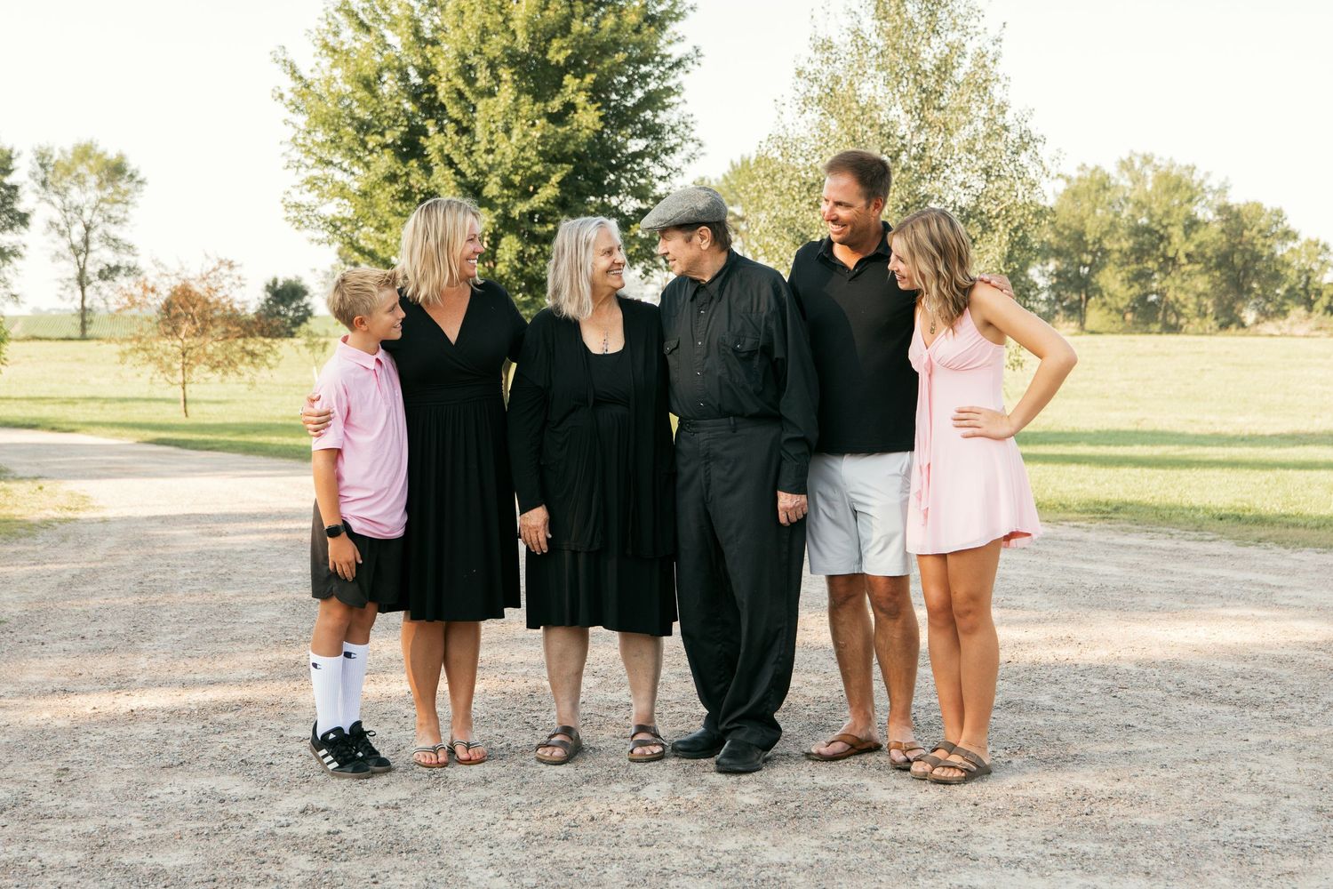 Outdoor group photo with people dressed in black and white attire against a natural landscape.