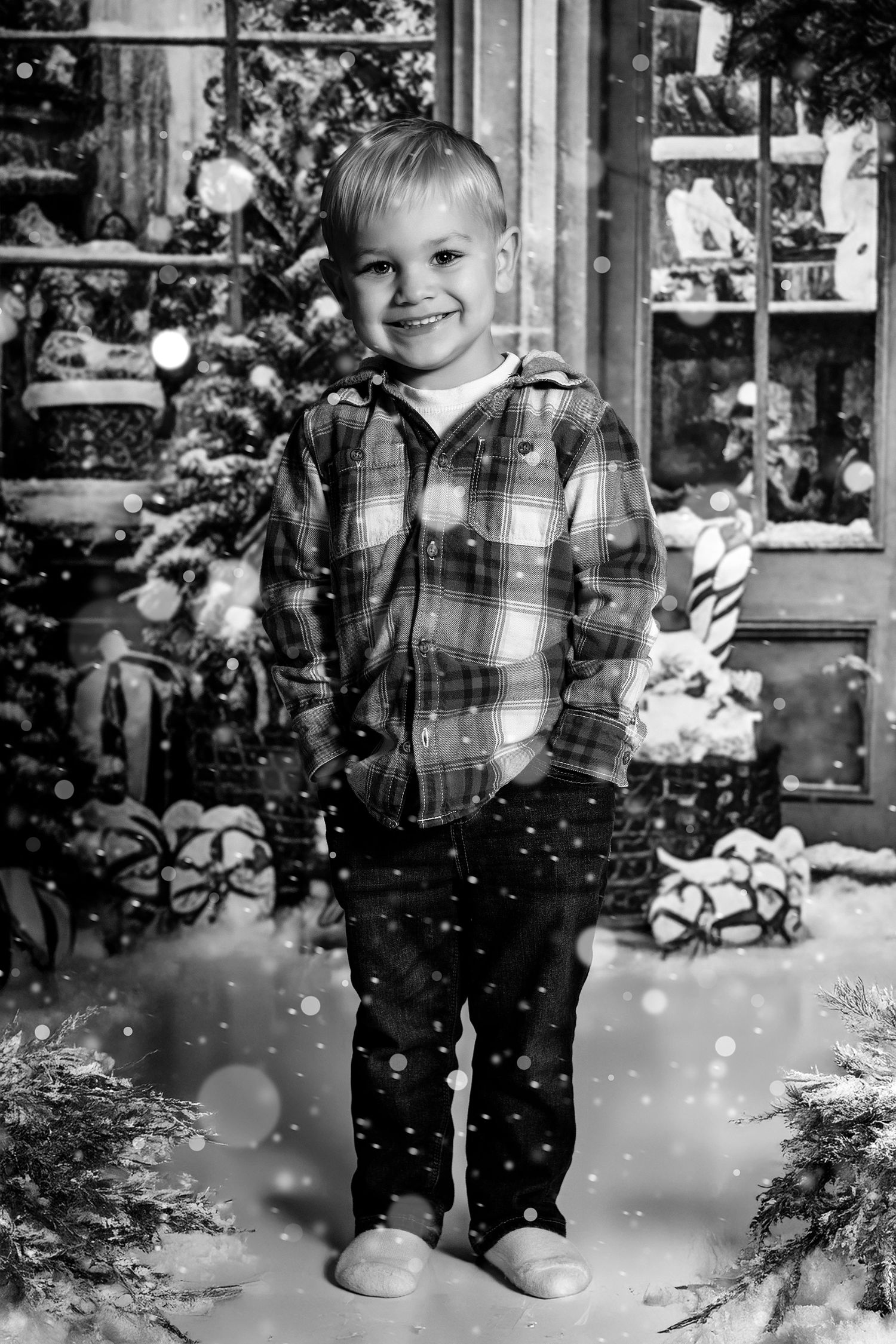 Black and white winter scene with falling snow and Christmas decorations in storefront setting.