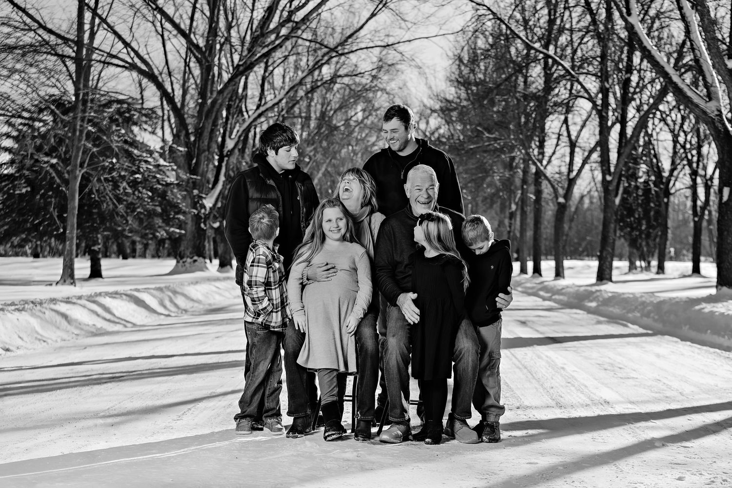 Black and white image of a family group standing close together in a wintry park setting.